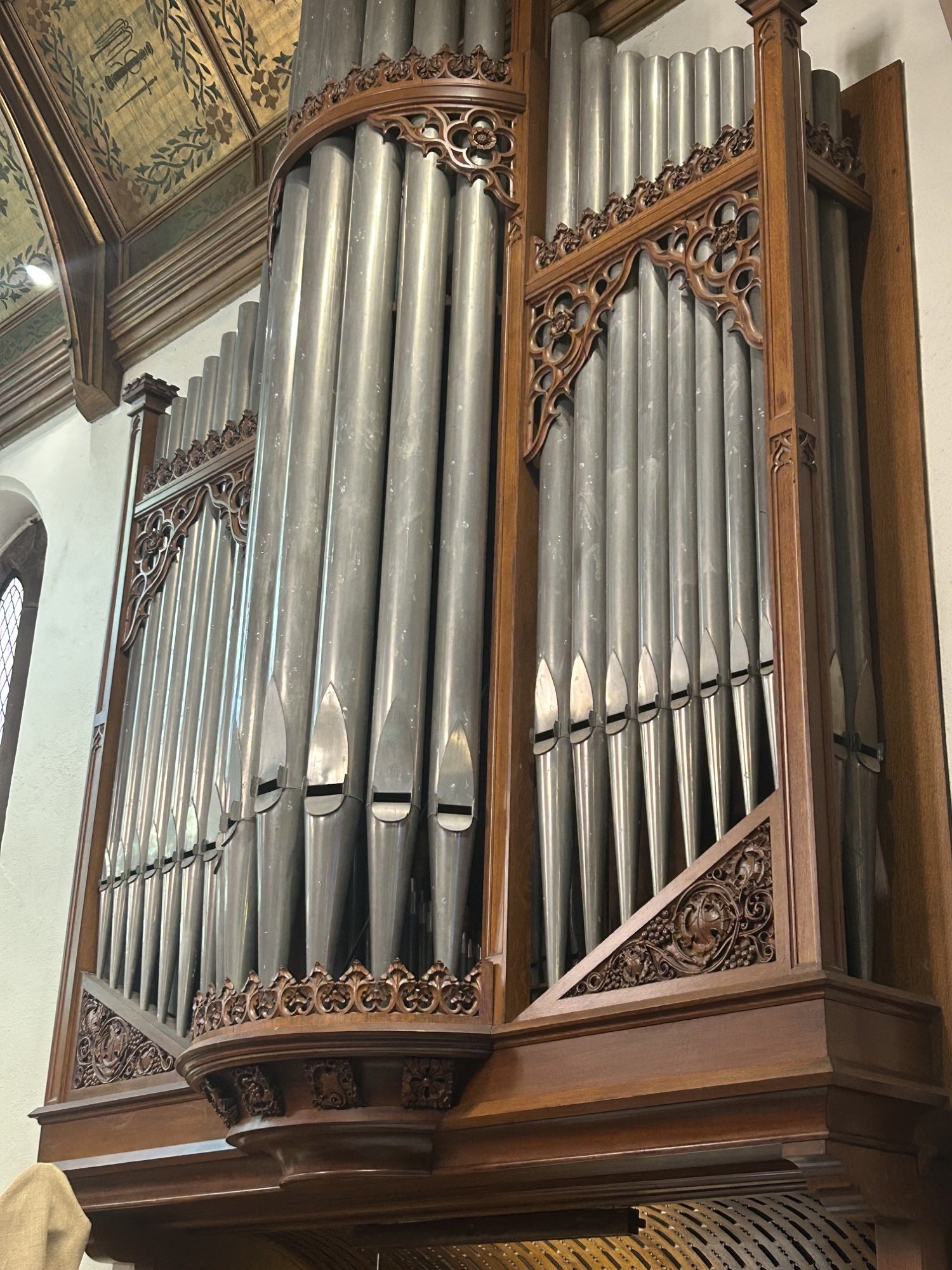 Close-up of a historic church pipe organ with tall silver pipes and ornate carved woodwork