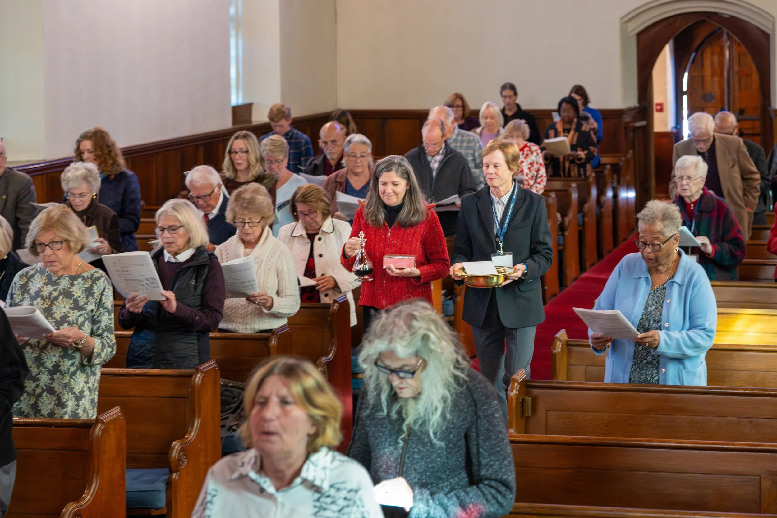 Congregation gathered in a church pews, holding printed programs during a service
