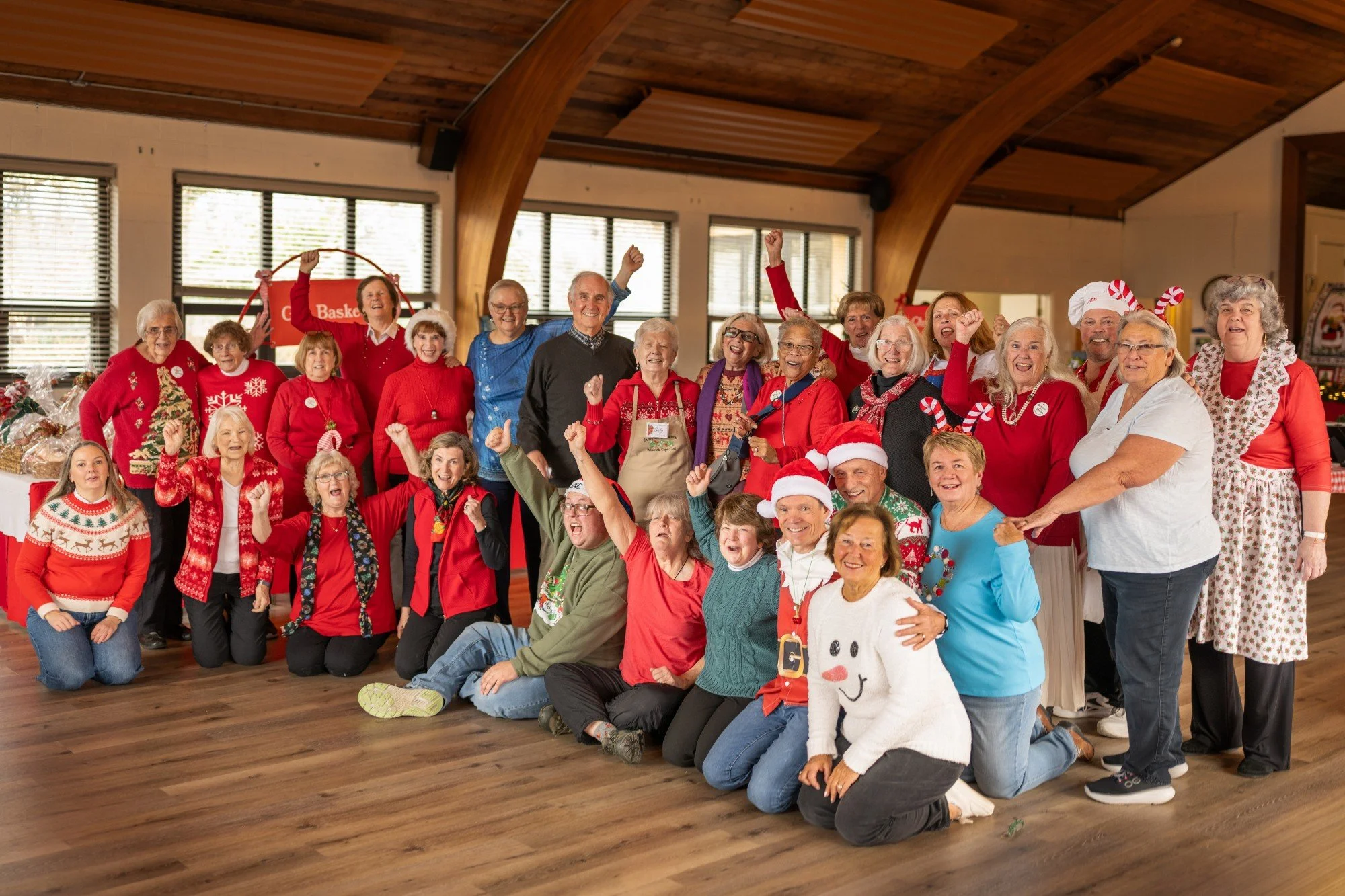 Large group of seniors wearing festive Christmas clothing and smiling together indoors