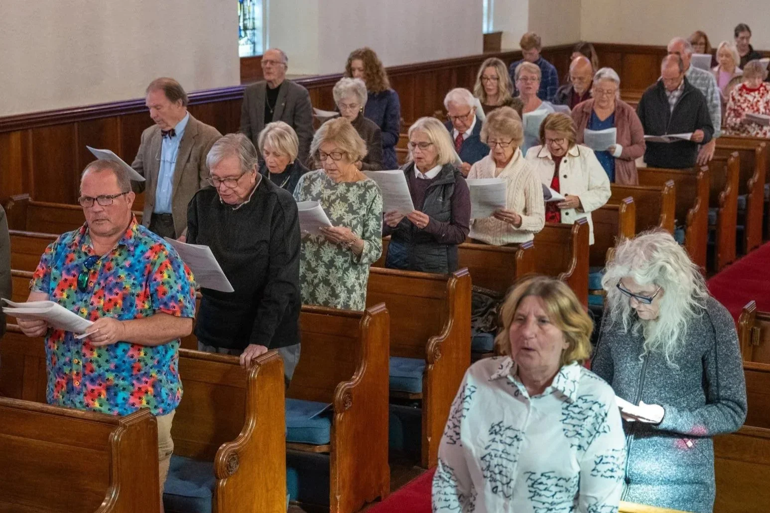 Congregation singing from printed hymn sheets inside a church.