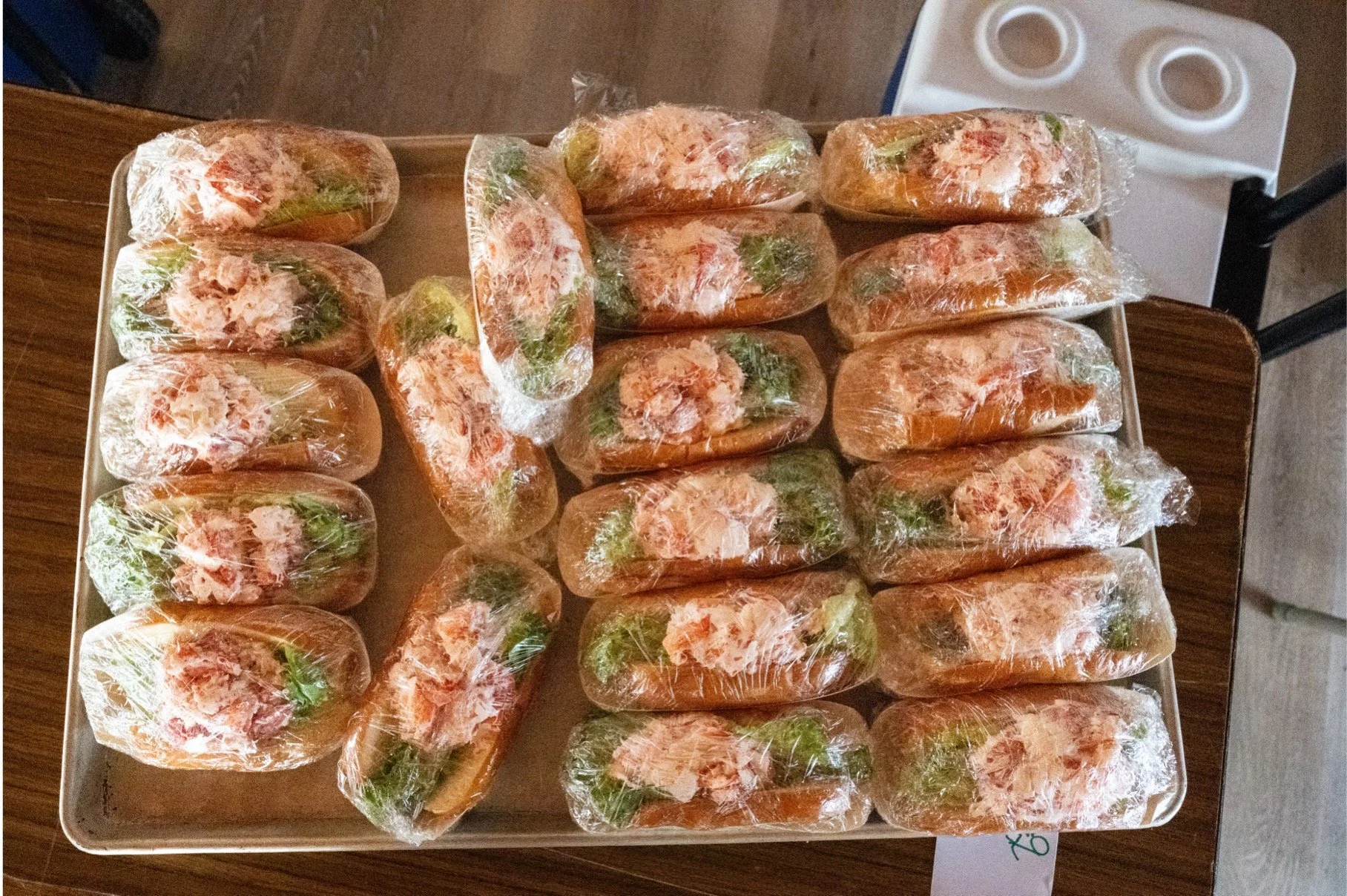 Tray of individually wrapped sandwiches filled with leafy greens and sliced meat