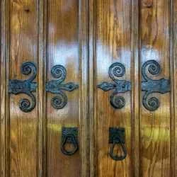 Close-up of ornate black wrought-iron scrollwork on a wooden double door