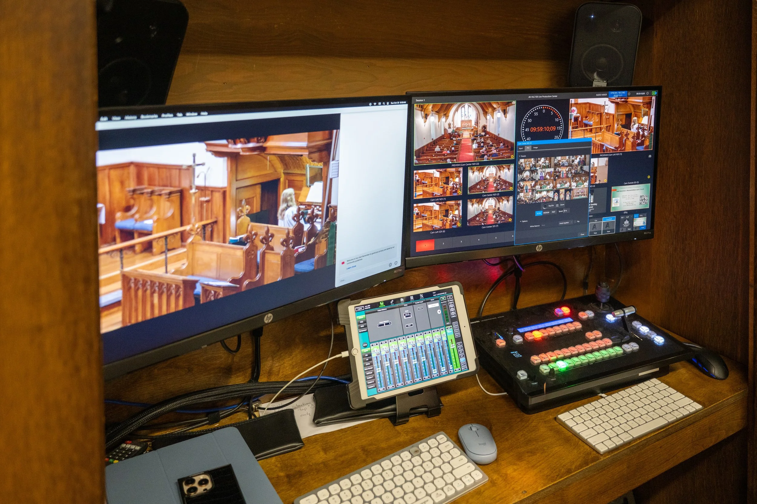 Church livestream production booth with camera-monitoring screens, video switcher, audio mixer, keyboards, and a tablet control panel