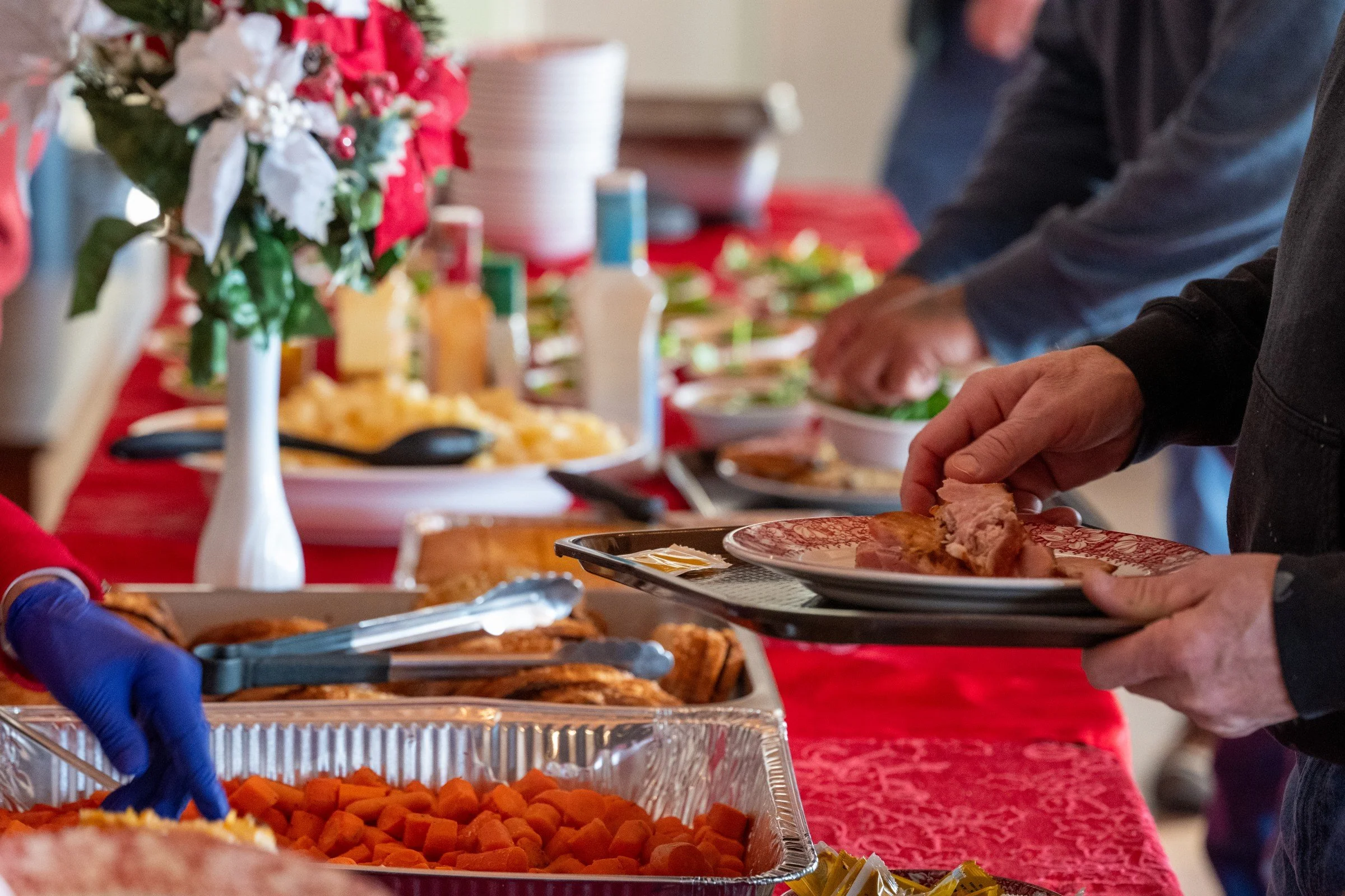 People serving roast meat and vegetables at a festive buffet table