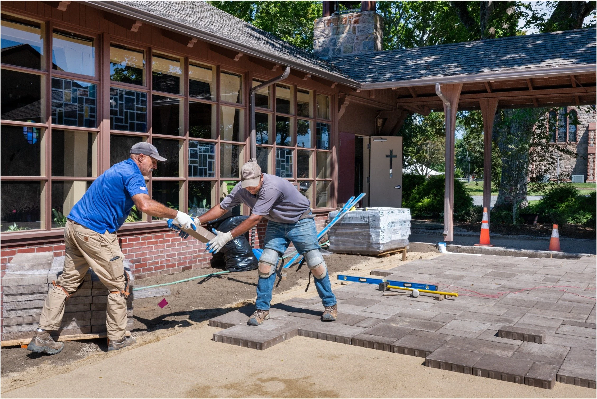 Two workers installing pavers outside a church building