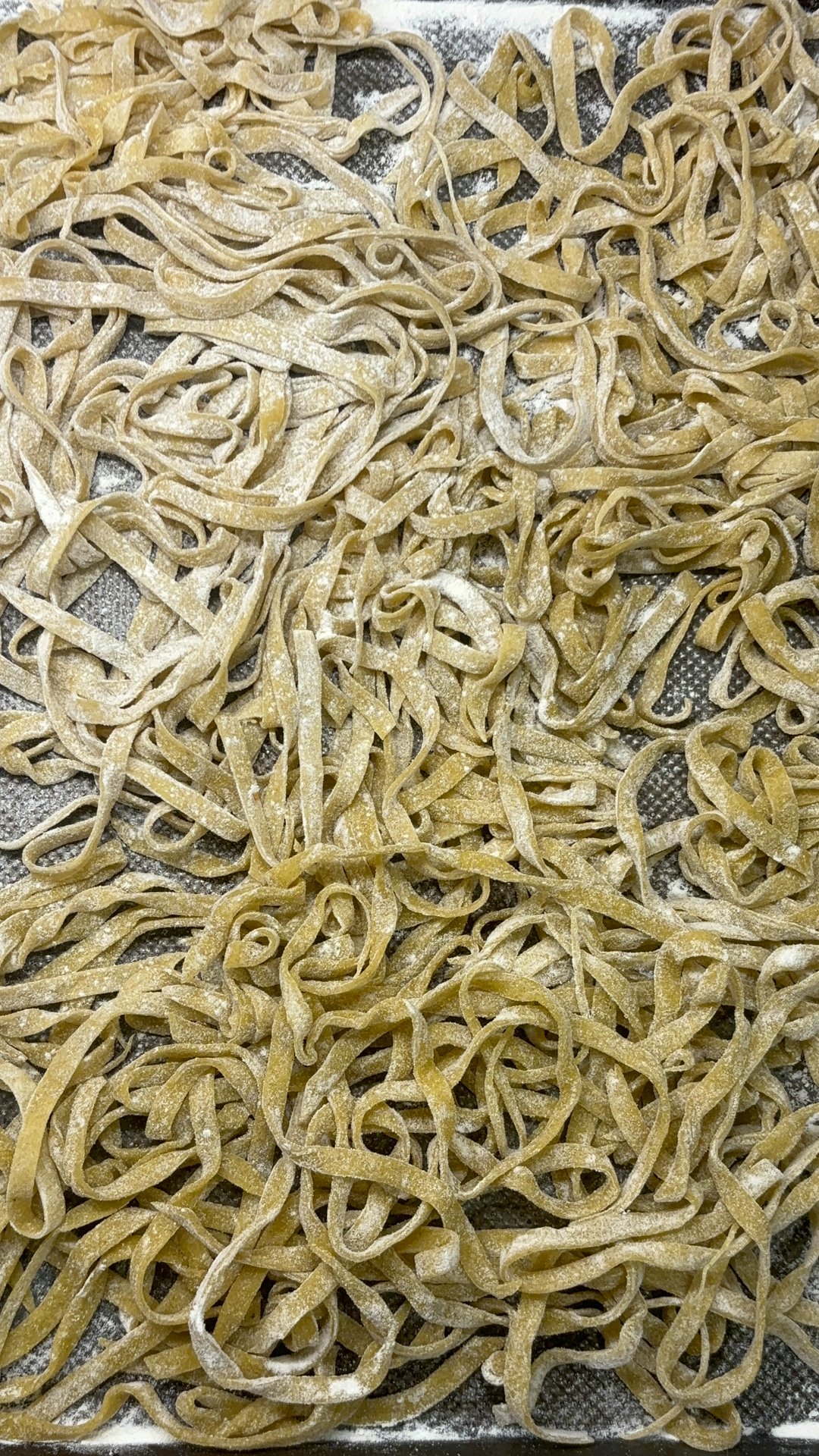 Raw, uncooked fettuccine pasta on a floured surface.