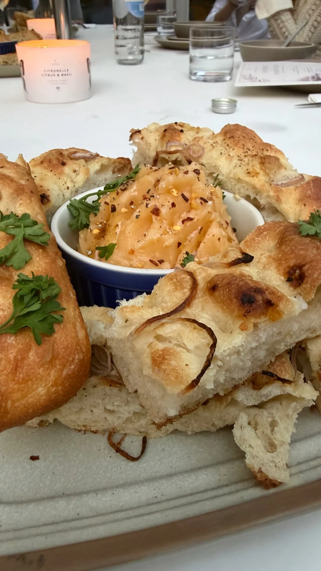 Chef Mike Catuosco - Gallery - Close-up of a bread basket with assorted baked bread and a dish of a creamy, spiced dish garnished with parsley on a dining table.