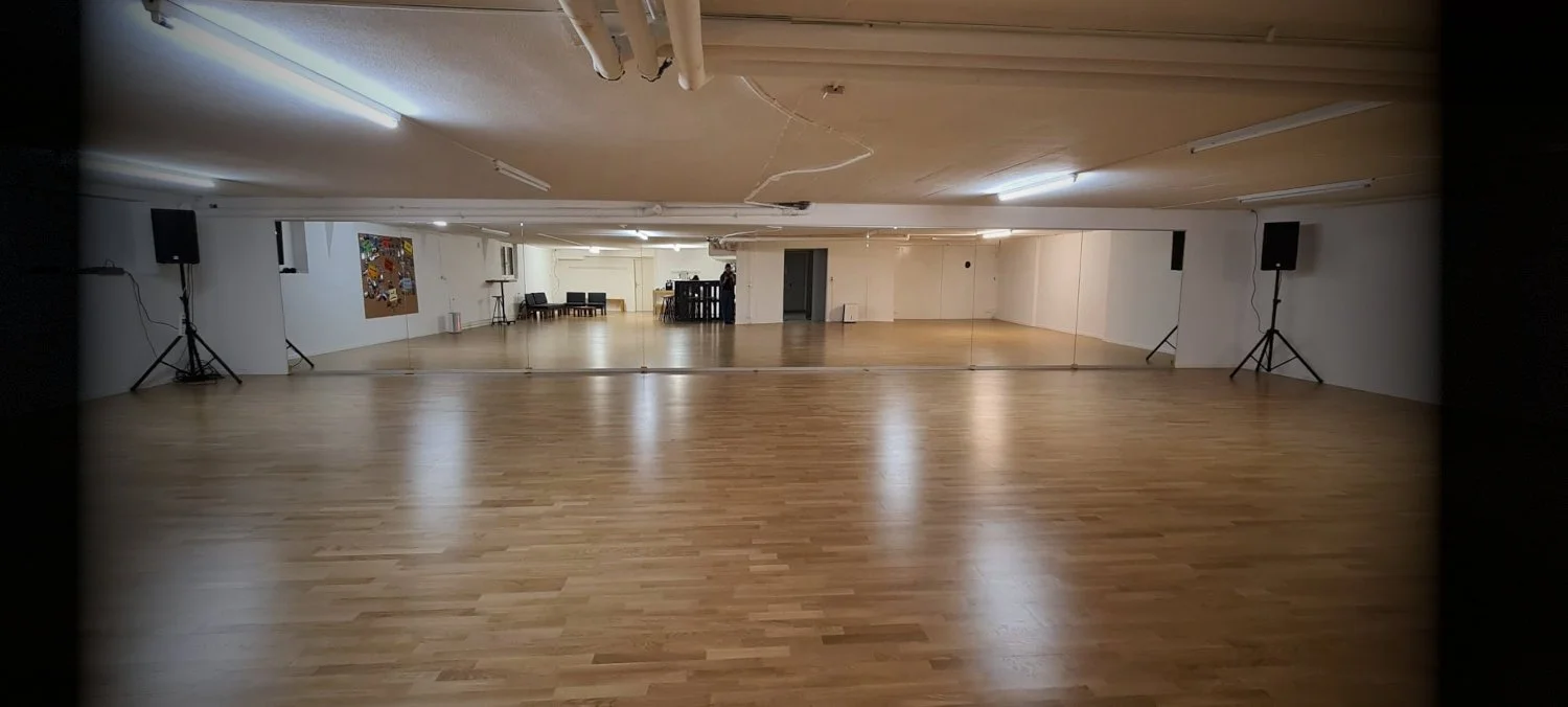 Empty dance studio for rent in Zurich with wooden floor and warm lighting