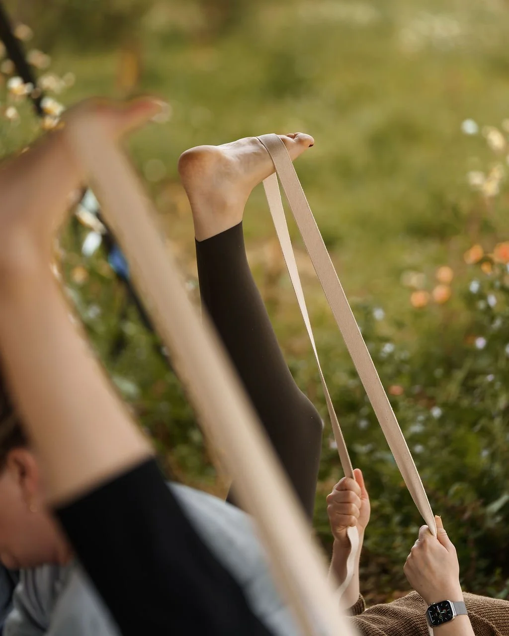 Woman practising a restorative yoga stretch with a yoga strap during an outdoor yin yoga and sound healing session in Mallorca