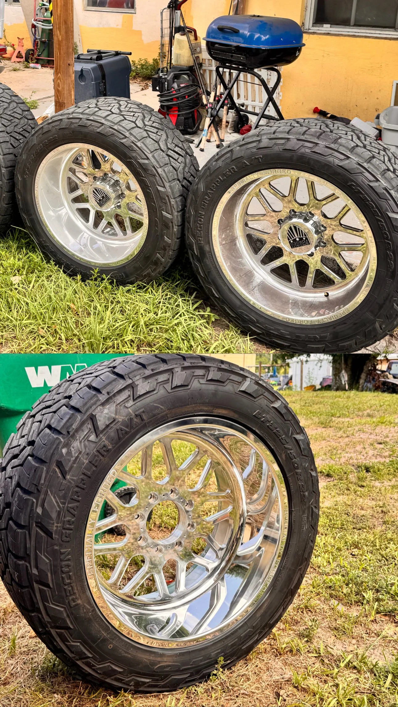 Side and front view of truck tires with chrome rims in an outdoor setting, with a grassy ground and a yellow building in the background.