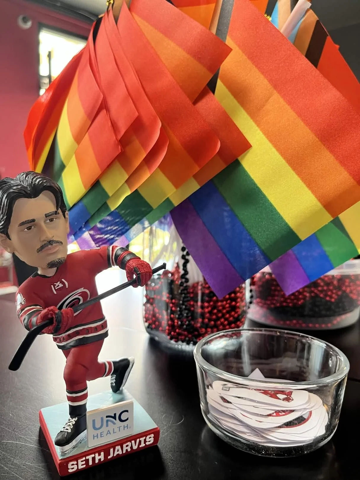 A bobblehead figurine of hockey player Seth Jarvis holding a bunch of rainbow pride flags.