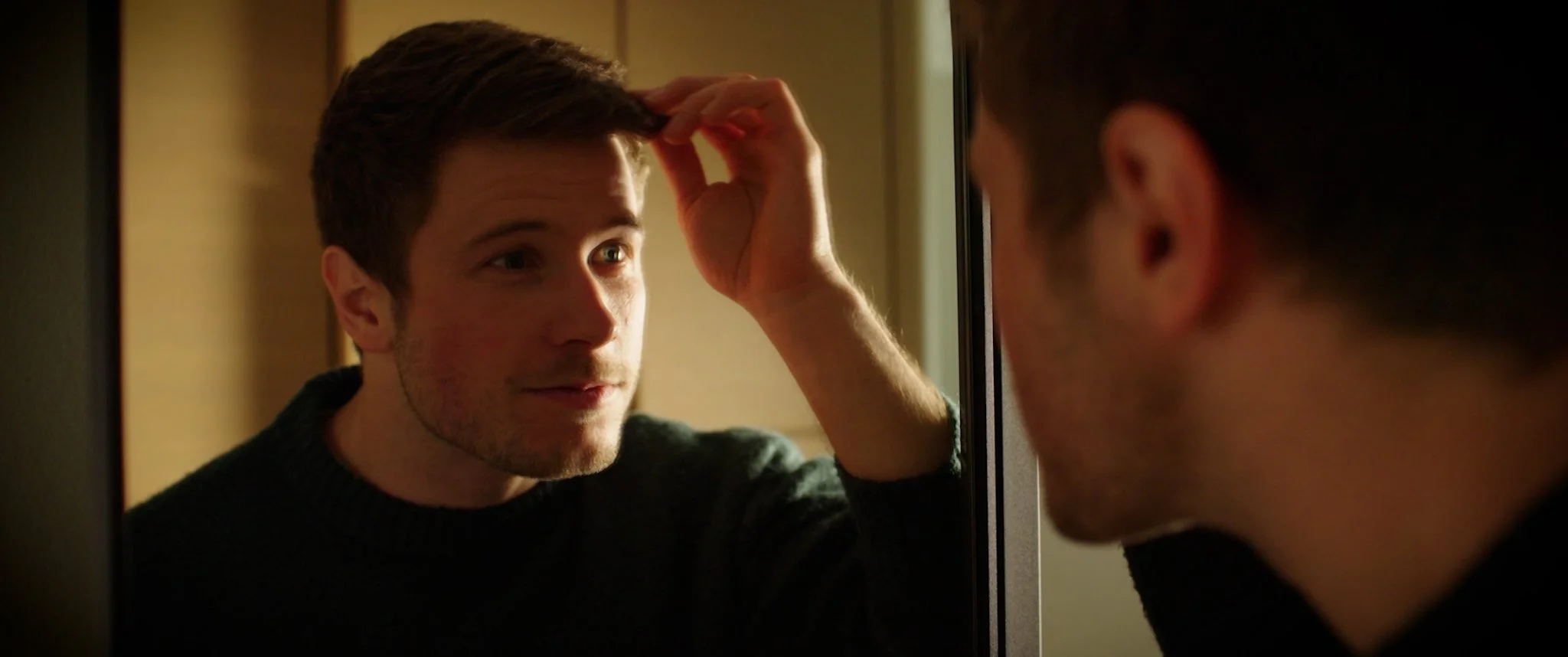 Cinematic Video, Phantomschmerz A young man looks into a mirror, touching his forehead as he examines his reflection.