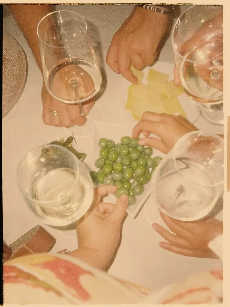 from above hands holding wine glasses and grabbing olives
