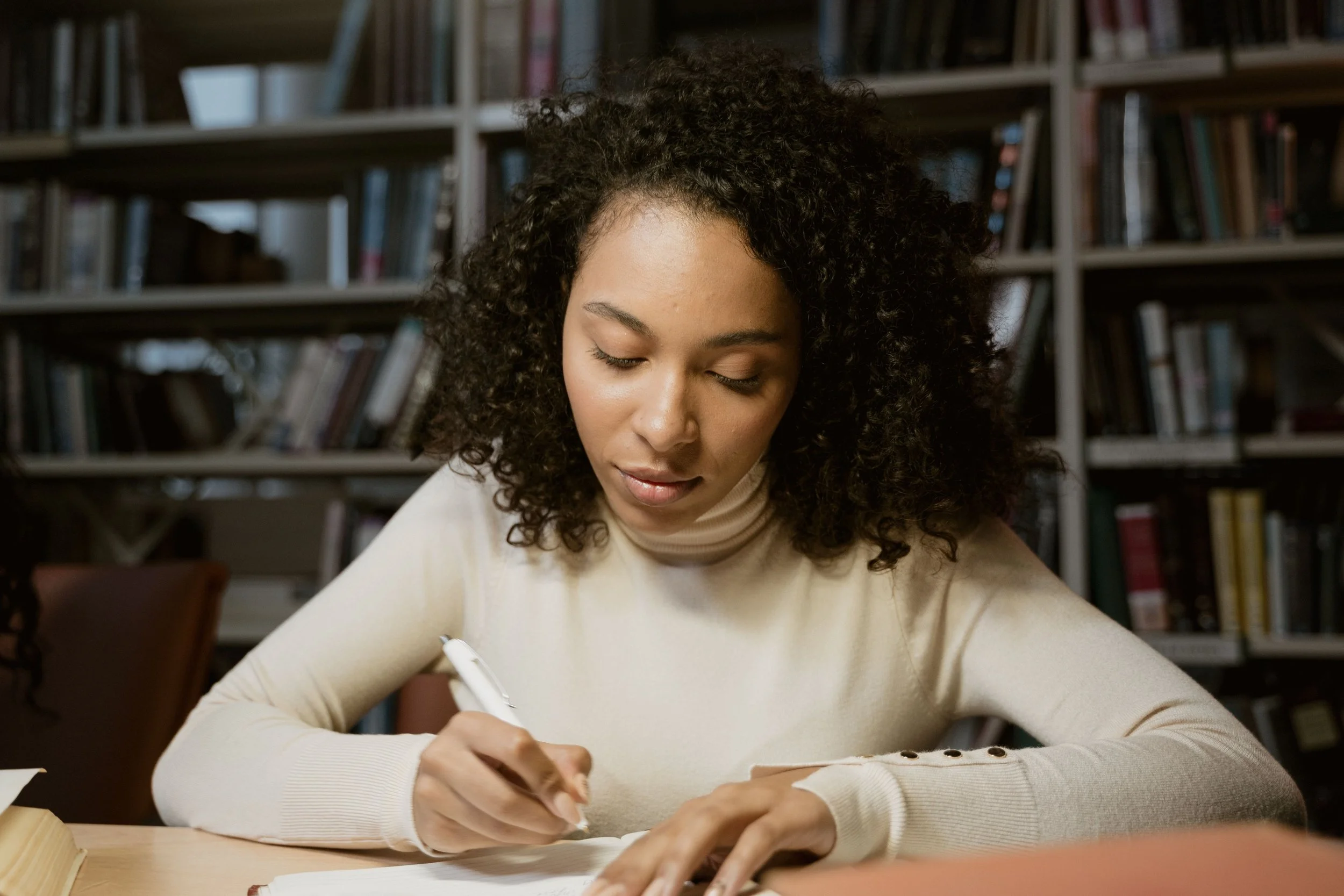 PIcture of a woman writing in library setting
