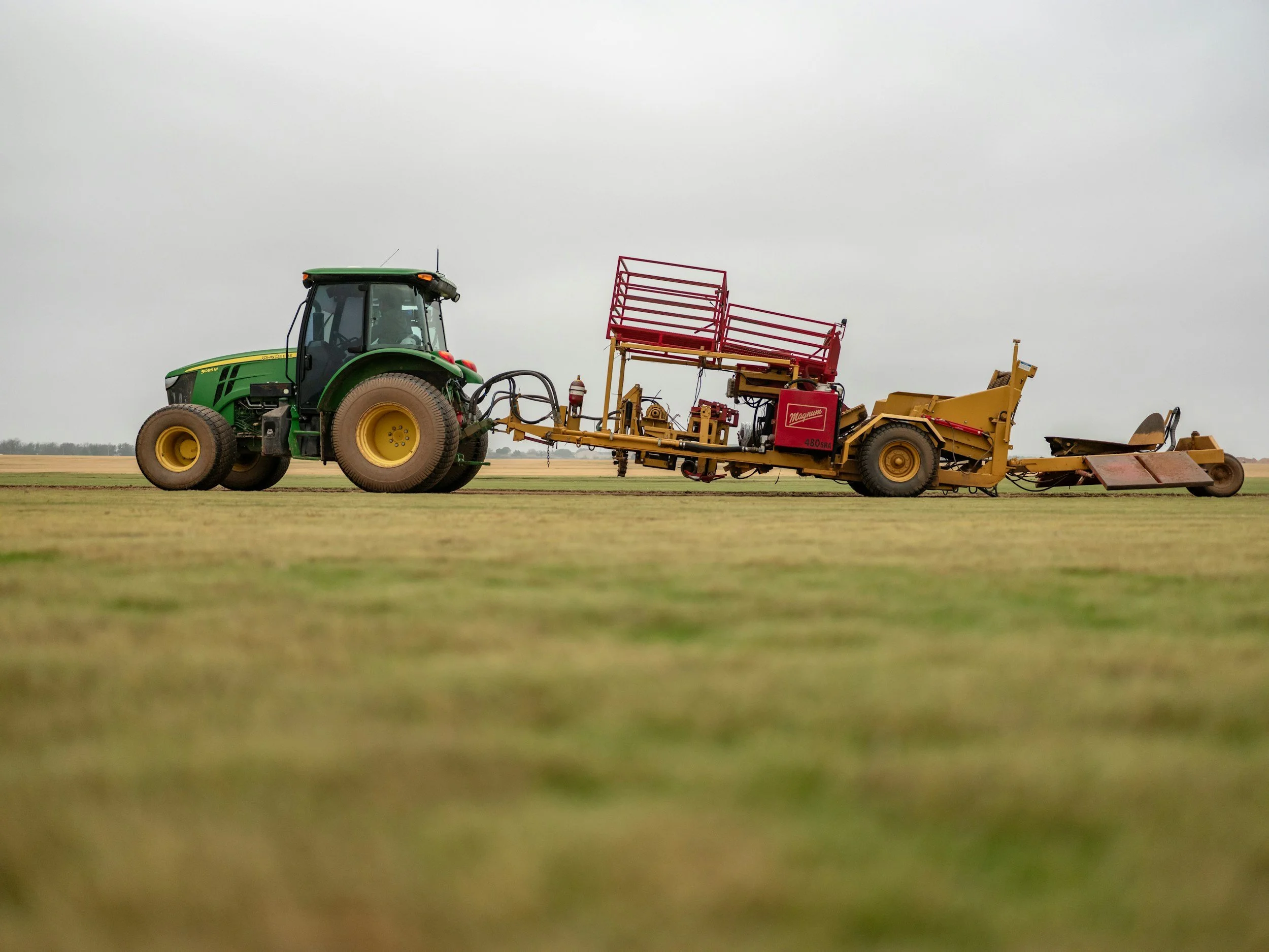 John Deere tractor towing a large agricultural planting implement across a field