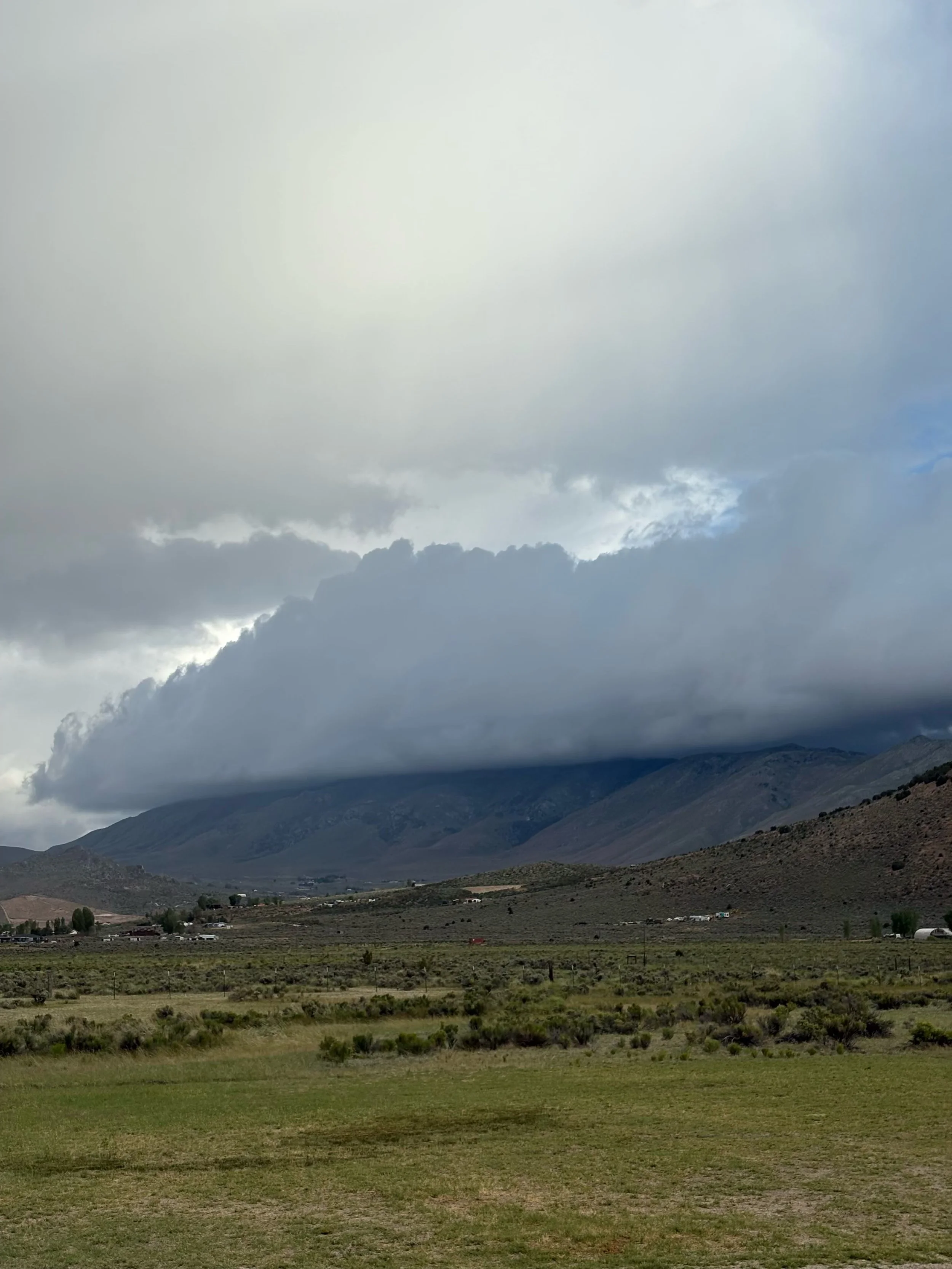 Storm clouds over a rugged mountain valley and grassy highland landscape