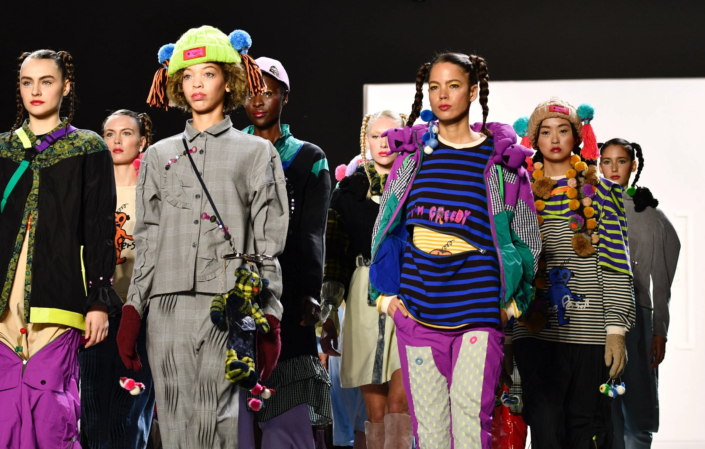 Models walking the runway in colorful, eclectic fashion with bold patterns, layered clothing, and playful accessories. Fashion Week Hong Kong, NYFW.