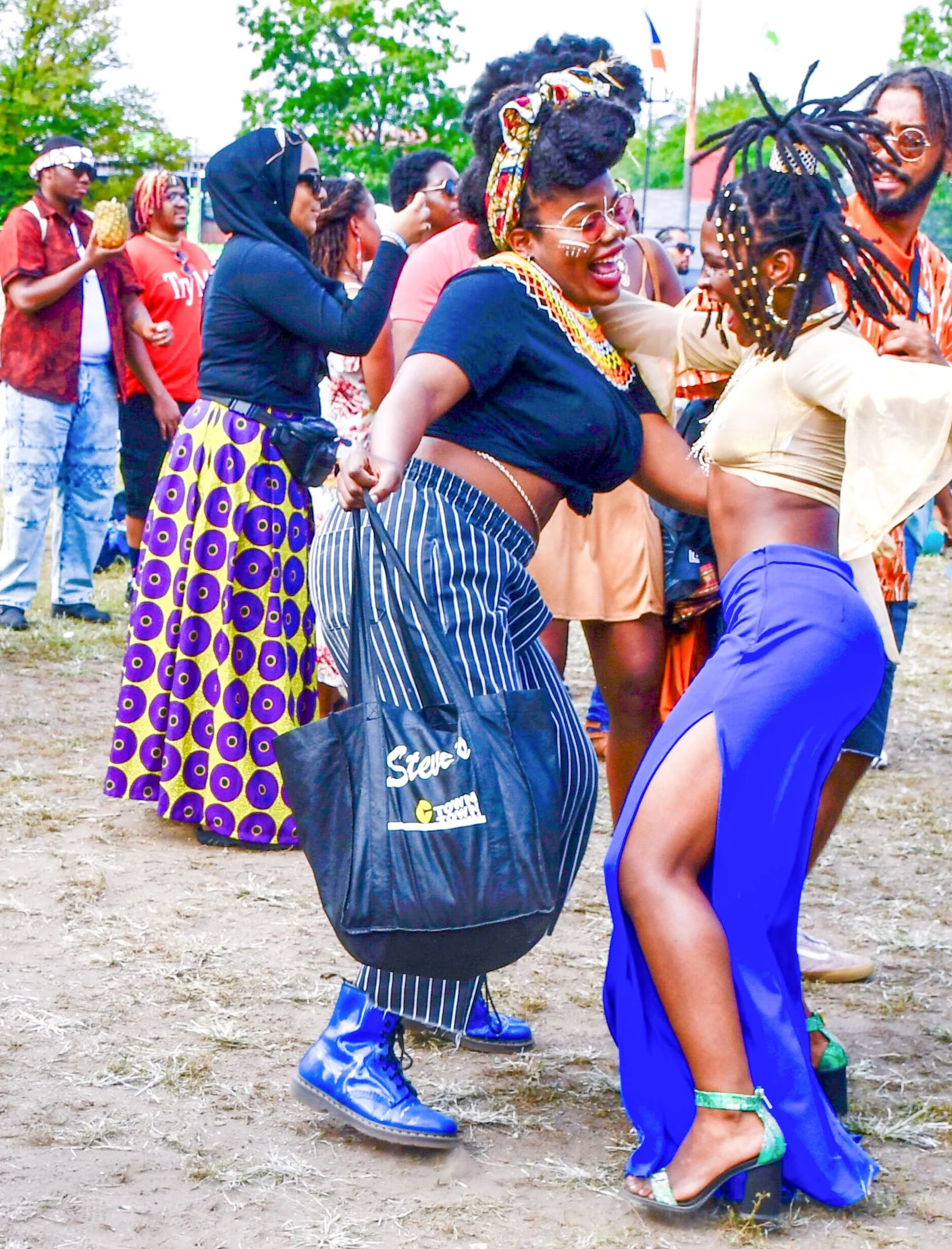 Group of people outdoors celebrating, dancing, and enjoying a festival or cultural event, with vibrant attire and accessories.