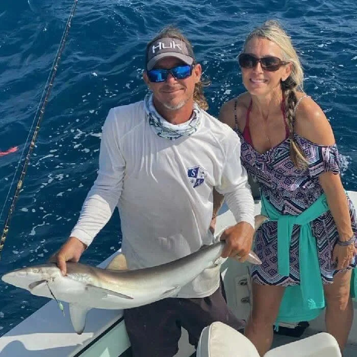 Couple aboard Cool Breeze holding a small shark catch