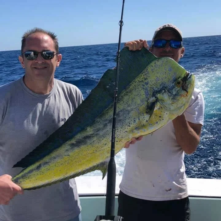 Two anglers holding a mahi-mahi catch aboard Cool Breeze