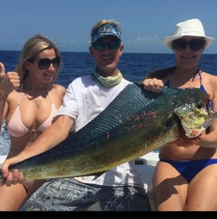 Group of three guests holding a mahi-mahi catch aboard Cool Breeze