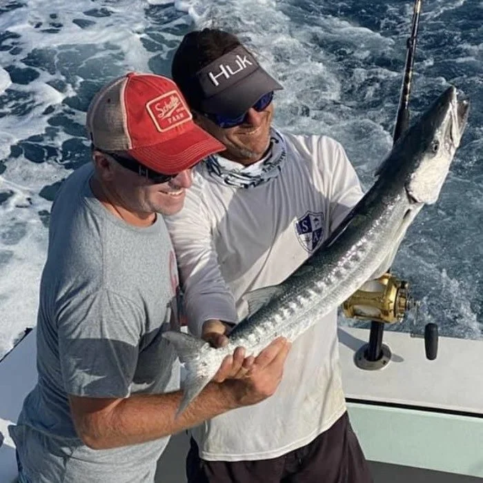 Angler holding a barracuda catch aboard Cool Breeze