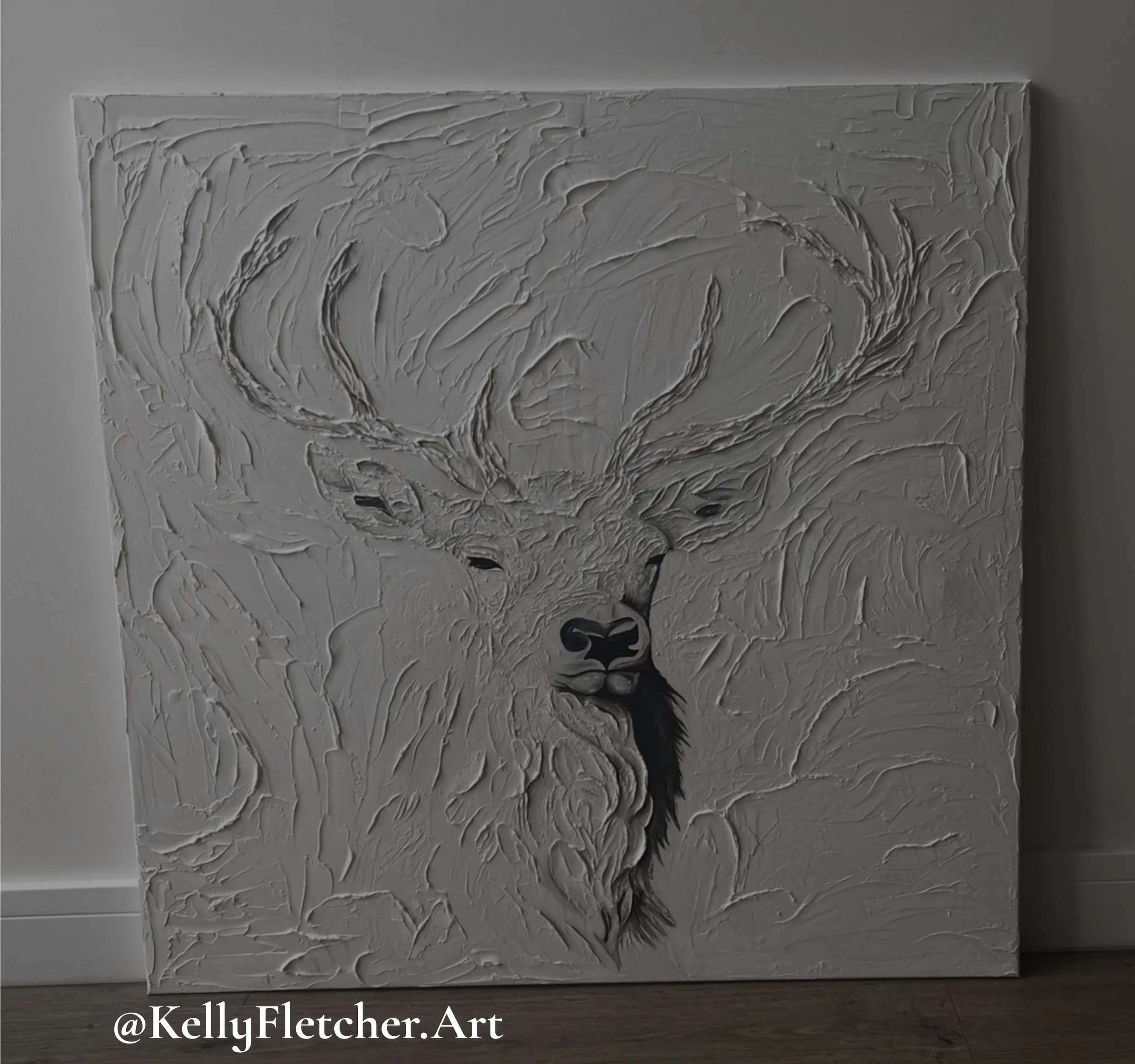 Textured white abstract painting with swirling patterns and dark accents at the bottom, displayed on a wall.