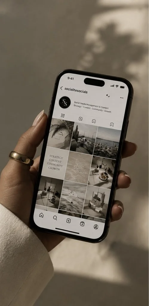 A person holding a smartphone displaying an Instagram profile called 'socialitesocials' with a grid of travel and cityscape photos.