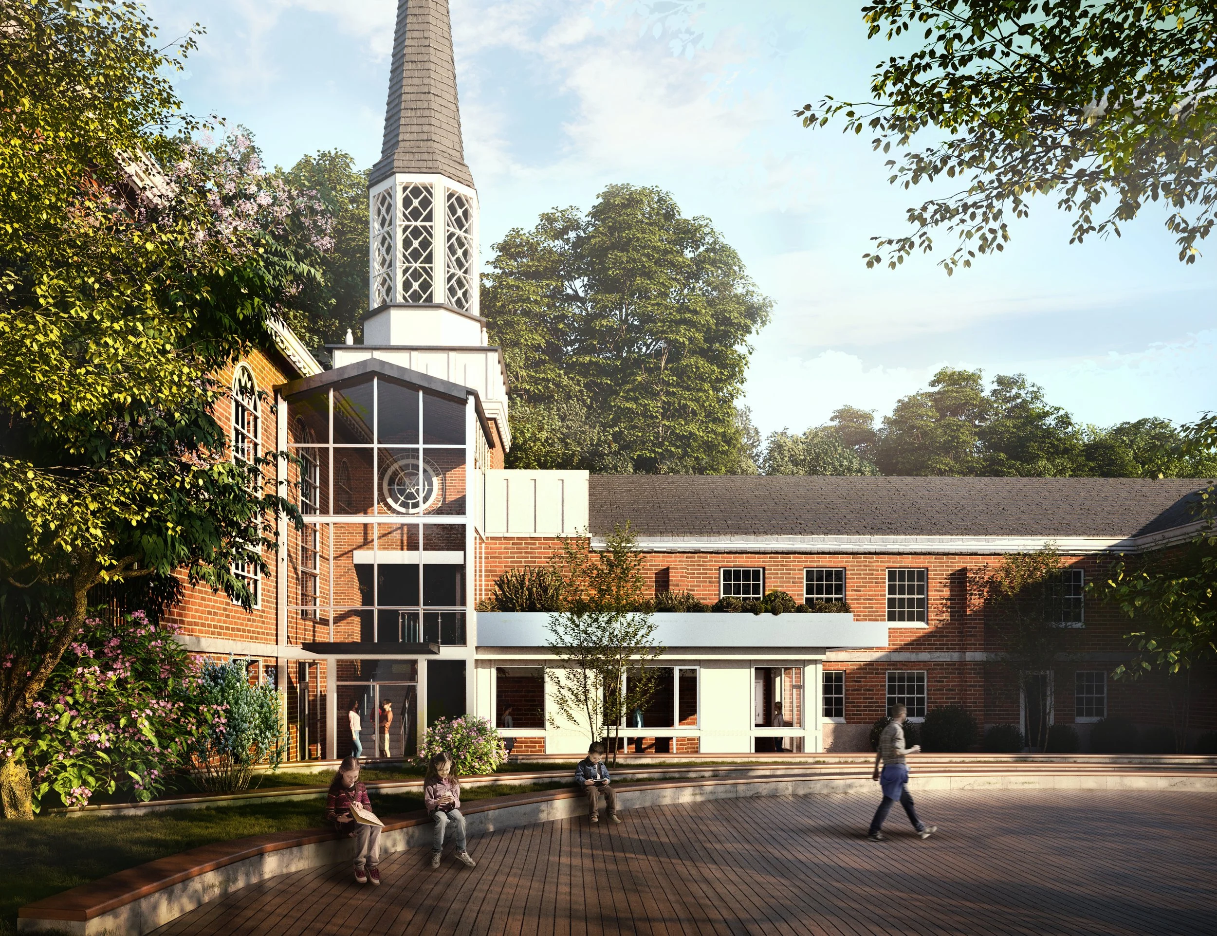 A brick church with a tall steeple surrounded by trees and blue sky, with children sitting on a curved wooden bench and people walking nearby.