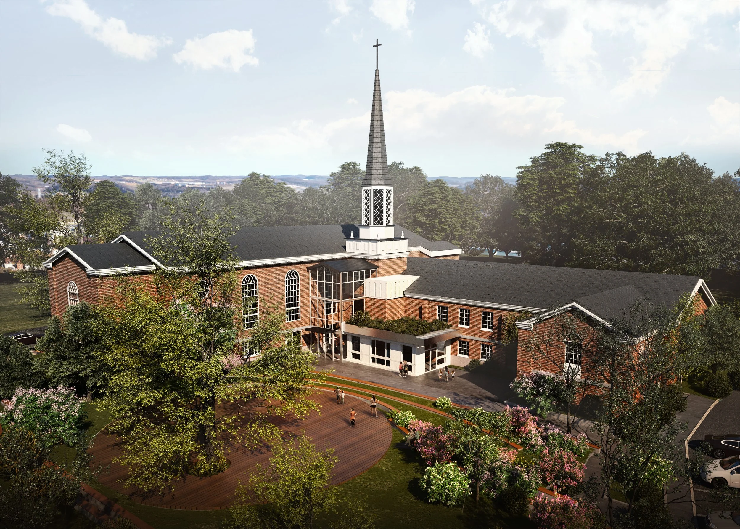 A church with a tall steeple and cross, surrounded by trees, shrubs, and flowers, with visitors walking on the brick walkway and parking lot in the foreground.