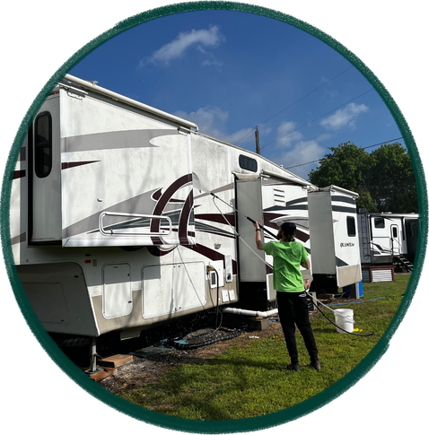 Person cleaning an RV outdoors under a partly cloudy sky.
