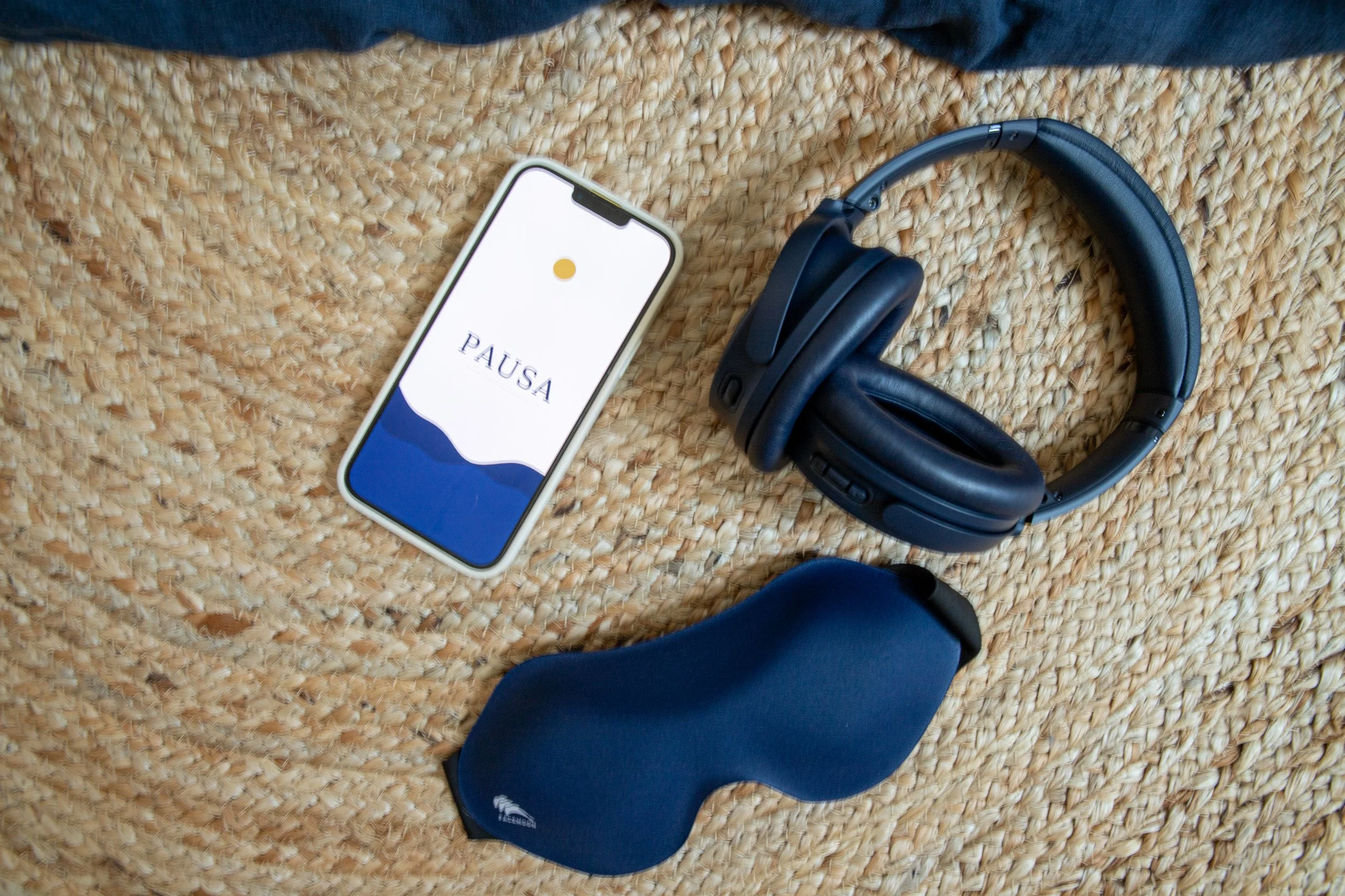 Audífonos, celular con PAUSA y antifaz, elementos para acompañar una práctica de Yoga Nidra.