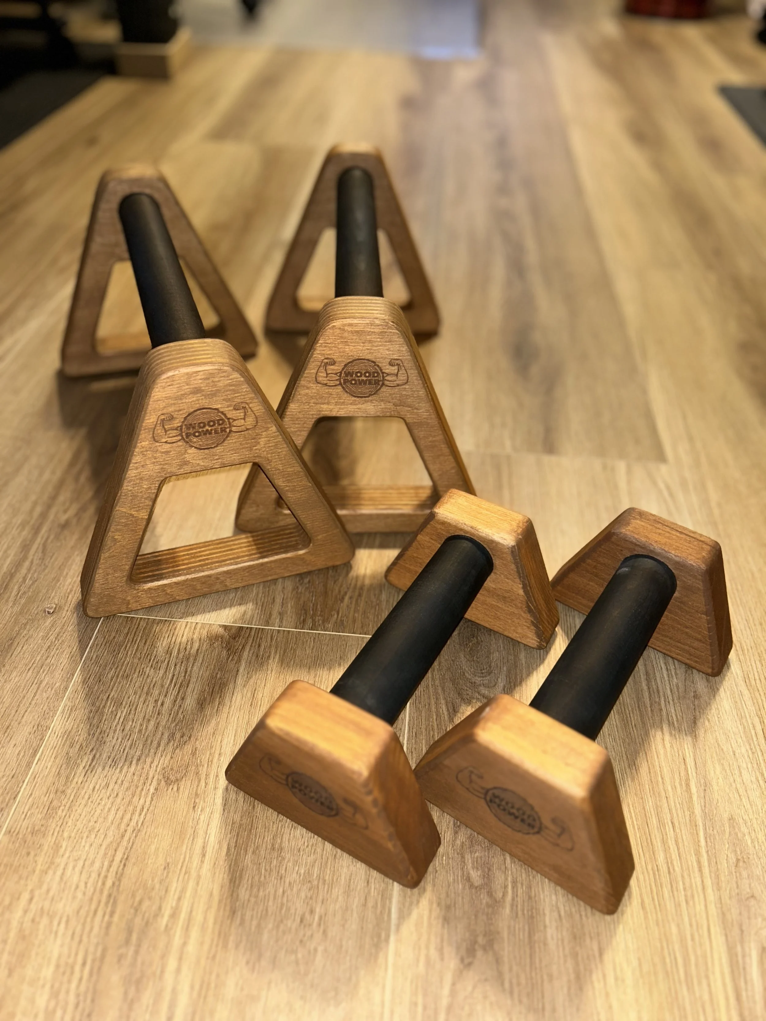 Wooden push-up bars with black handles on a wooden floor.