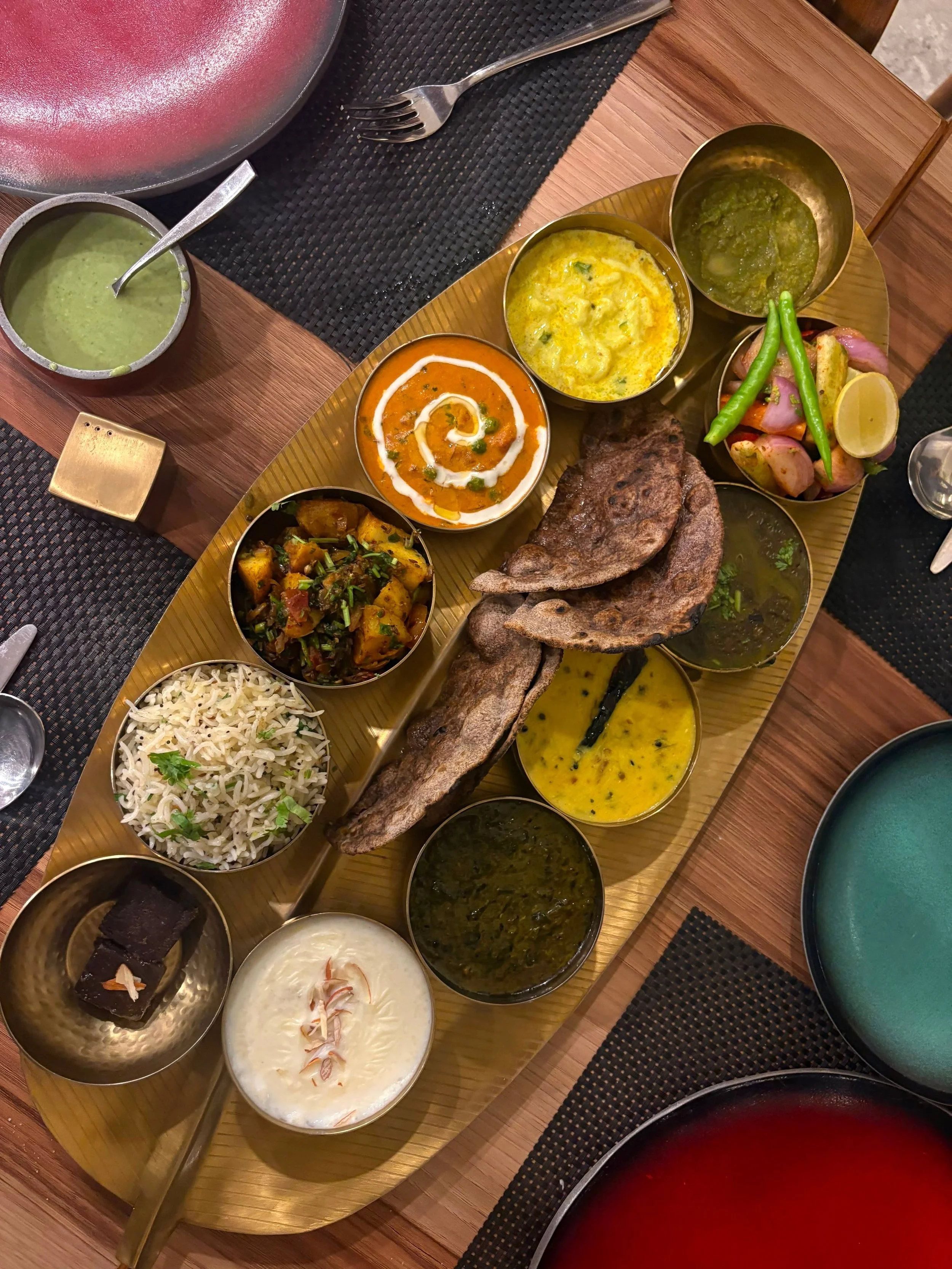 Assorted Indian dishes on a serving tray, including rice, curries, grilled bread, vegetables, and desserts made for affordable corporate delivery