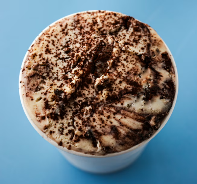 A cup of ice cream topped with chocolate shavings on a blue background.