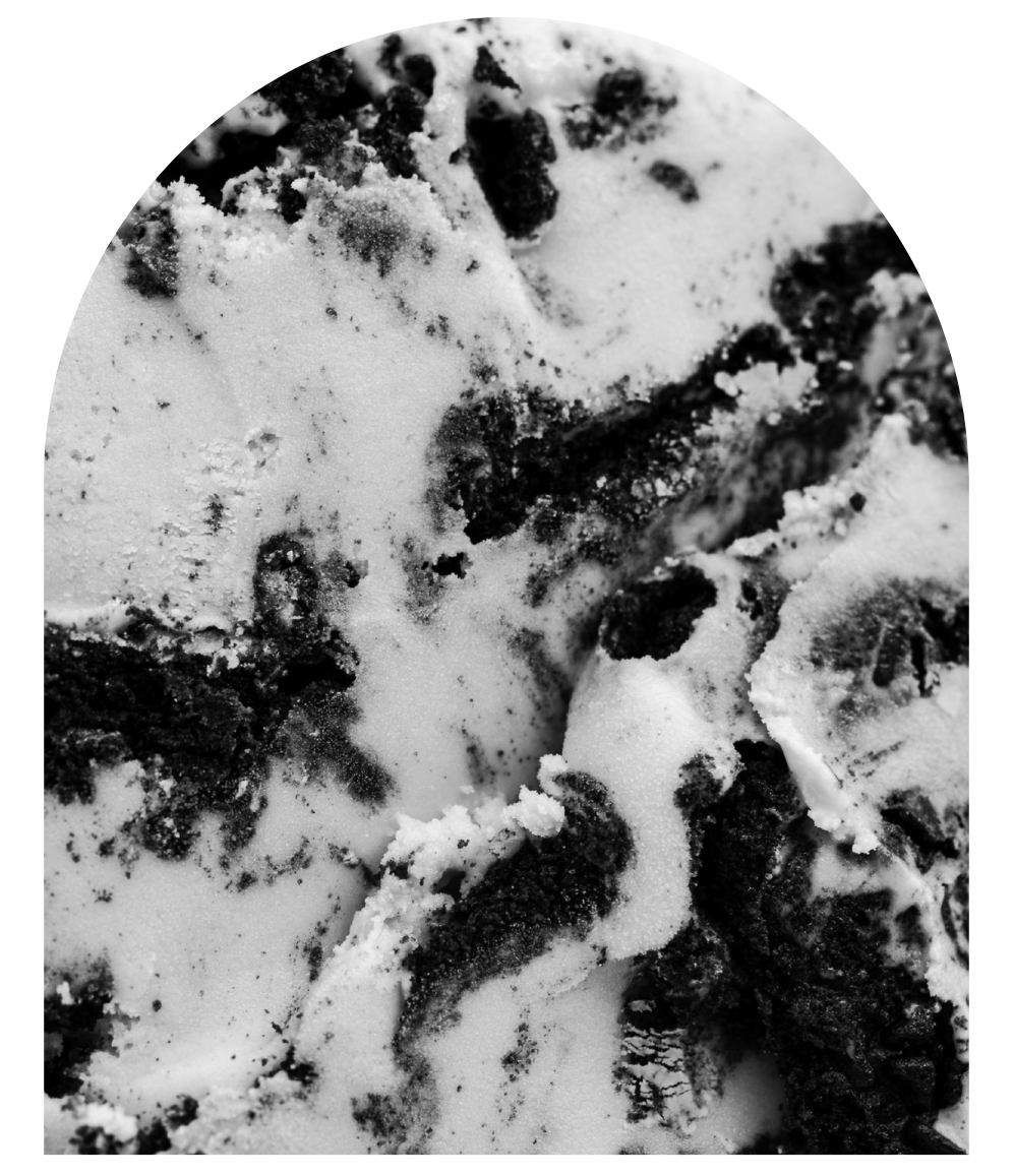A black and white close-up shot of ice cream texture with cookie mix-ins.