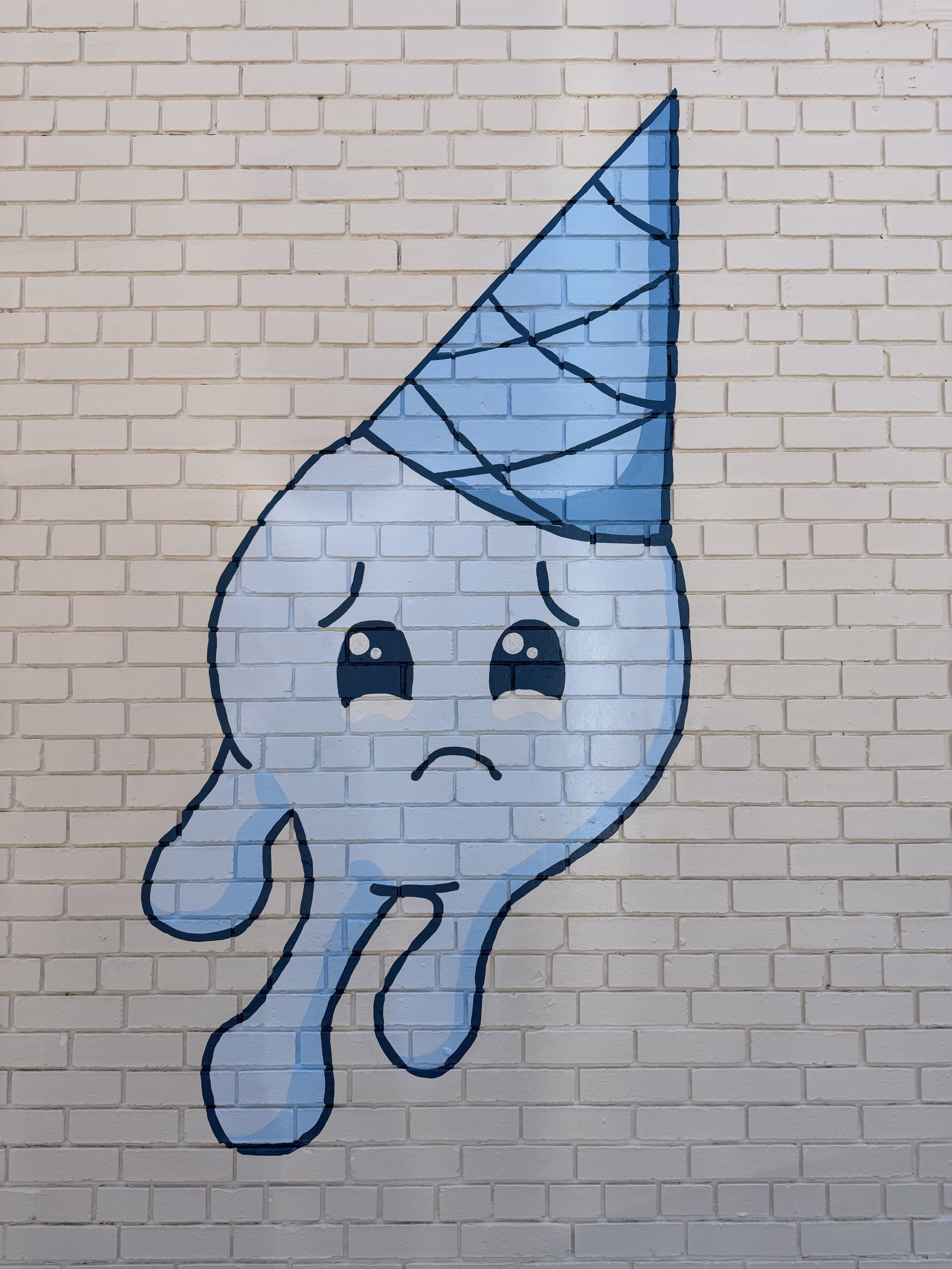 Street art of a sad cartoon giraffe painted on a white brick wall, with a blue body and dark blue outline.