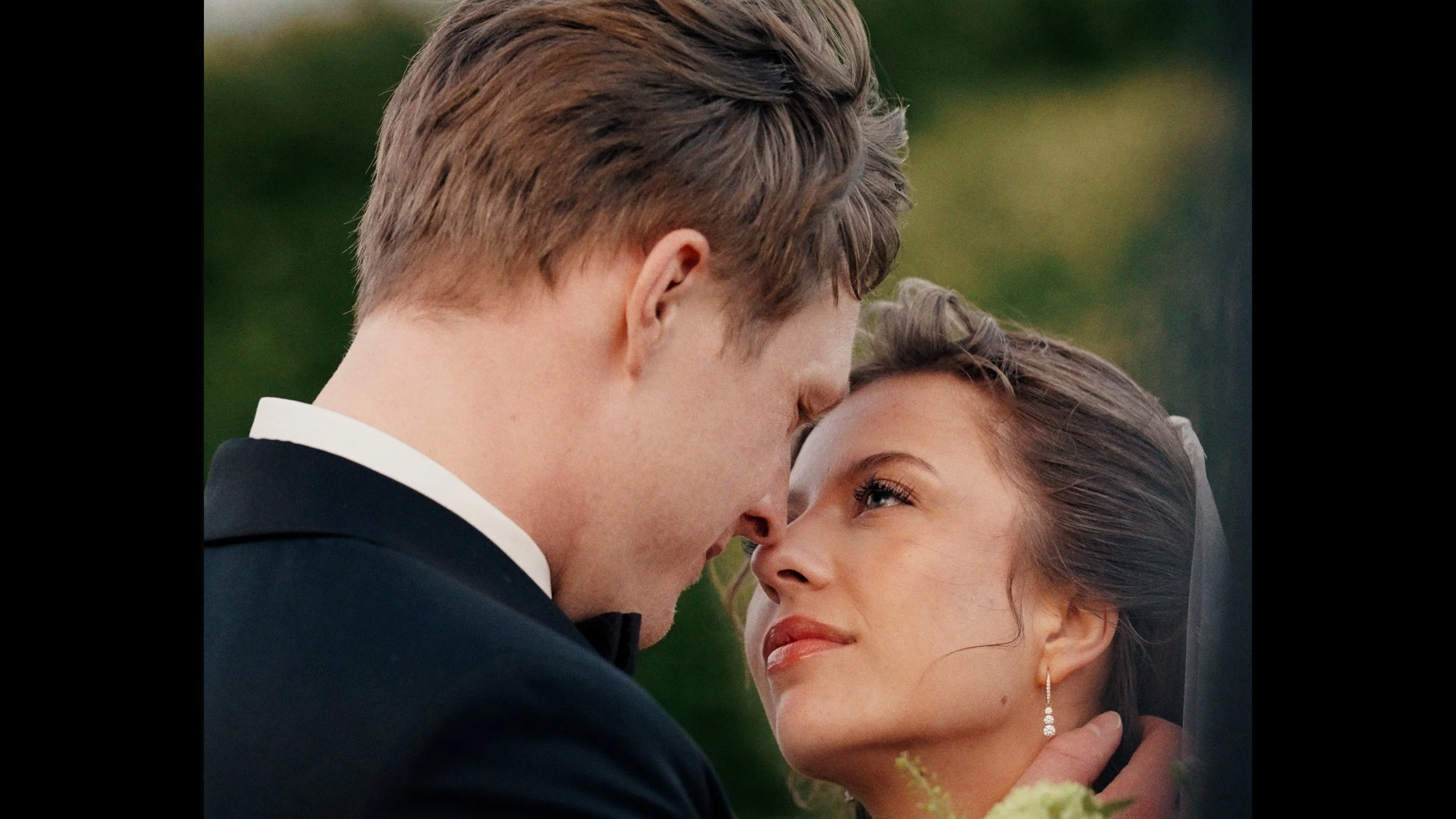 Ein Paar bei einer Hochzeit, das sich nahe kommt und sich liebevoll anschaut.