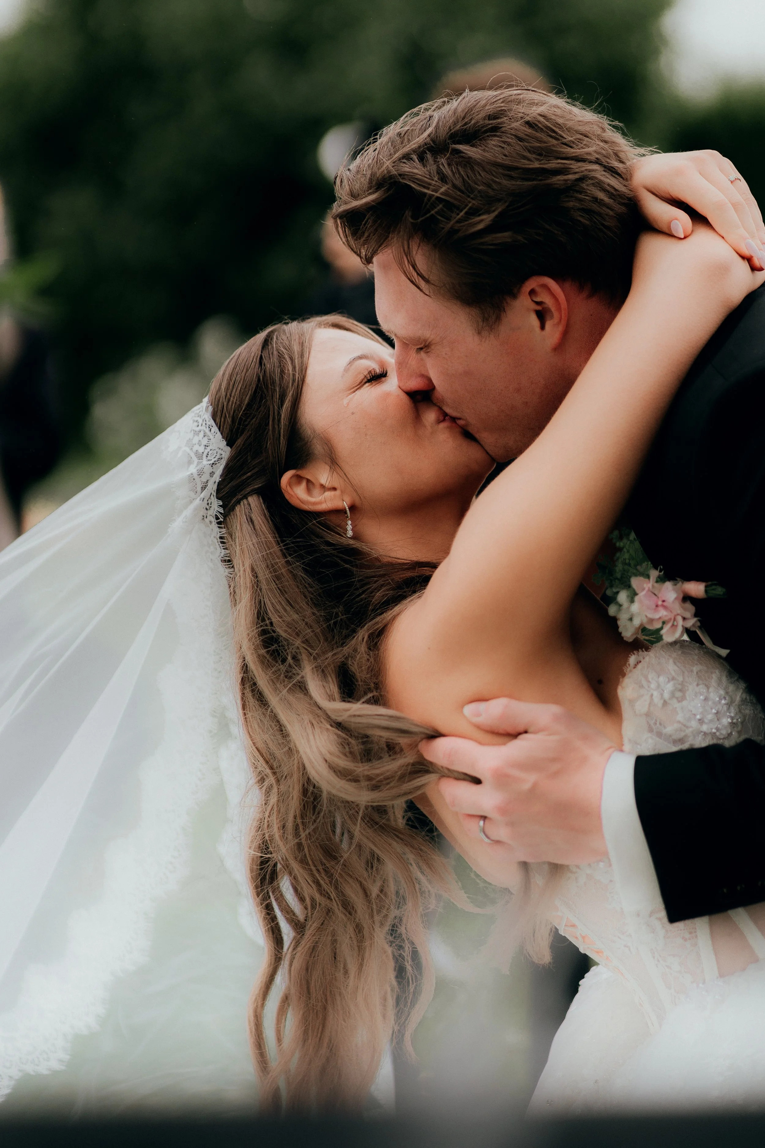 Braut und Bräutigam küssen sich bei ihrer Hochzeit im Freien.
