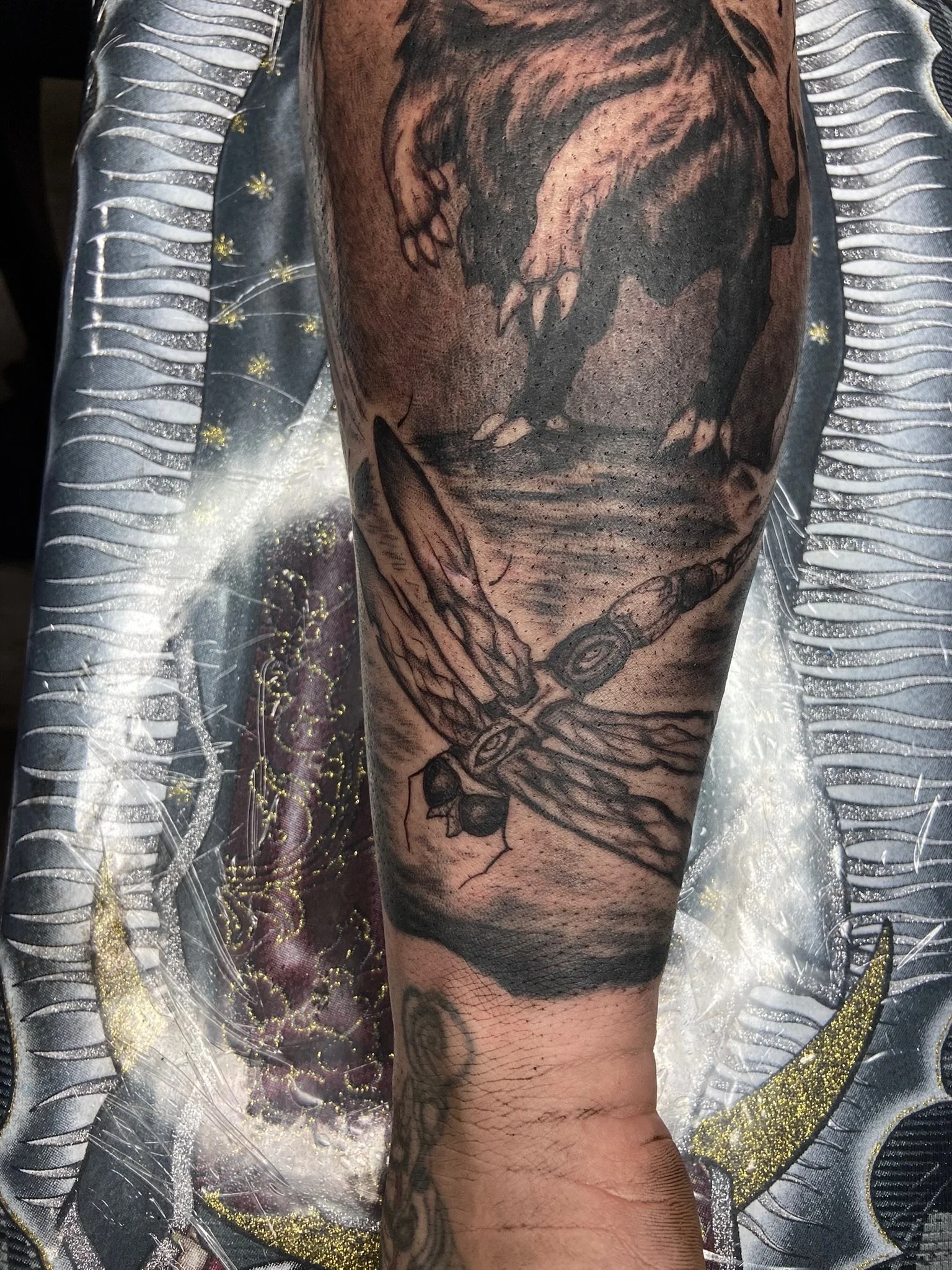 A detailed black and gray tattoo of a wolf hunting a deer on a person's forearm, with the fox's head near the wrist and the fox's body stretching upwards.