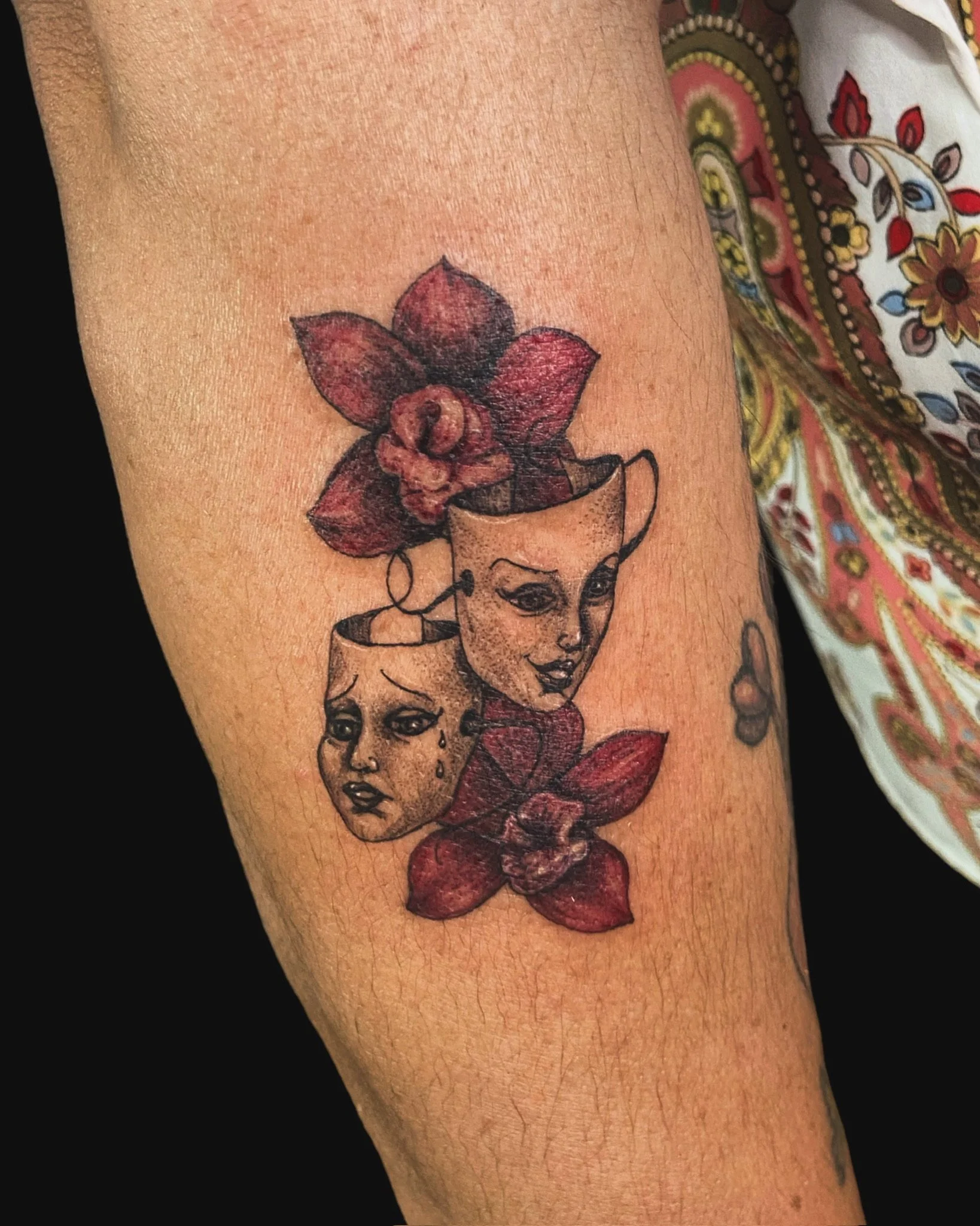 Tattoo of a woman's face with floral elements on the arm.