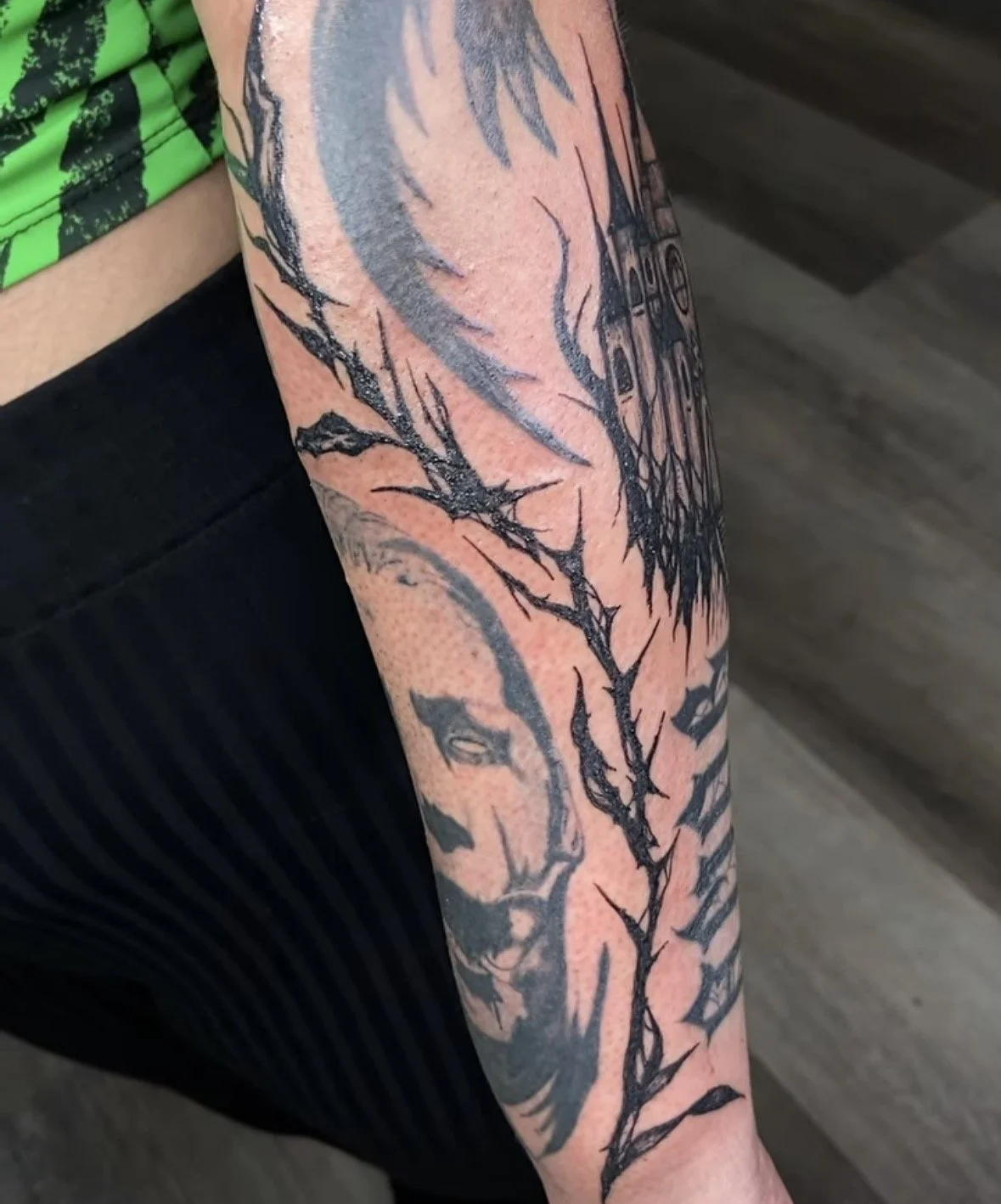 Black and gray tattoo on person's forearm featuring a dragon with spiky wings and a deer head with antlers by tattoo artist Agua at Floating Streams Tattoo in the Arts District of Downtown Los Angeles.