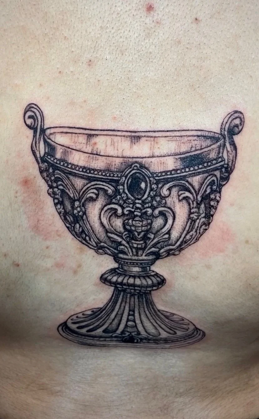Tattoo of an ornate antique chalice or goblet with detailed patterns and embellishments.
