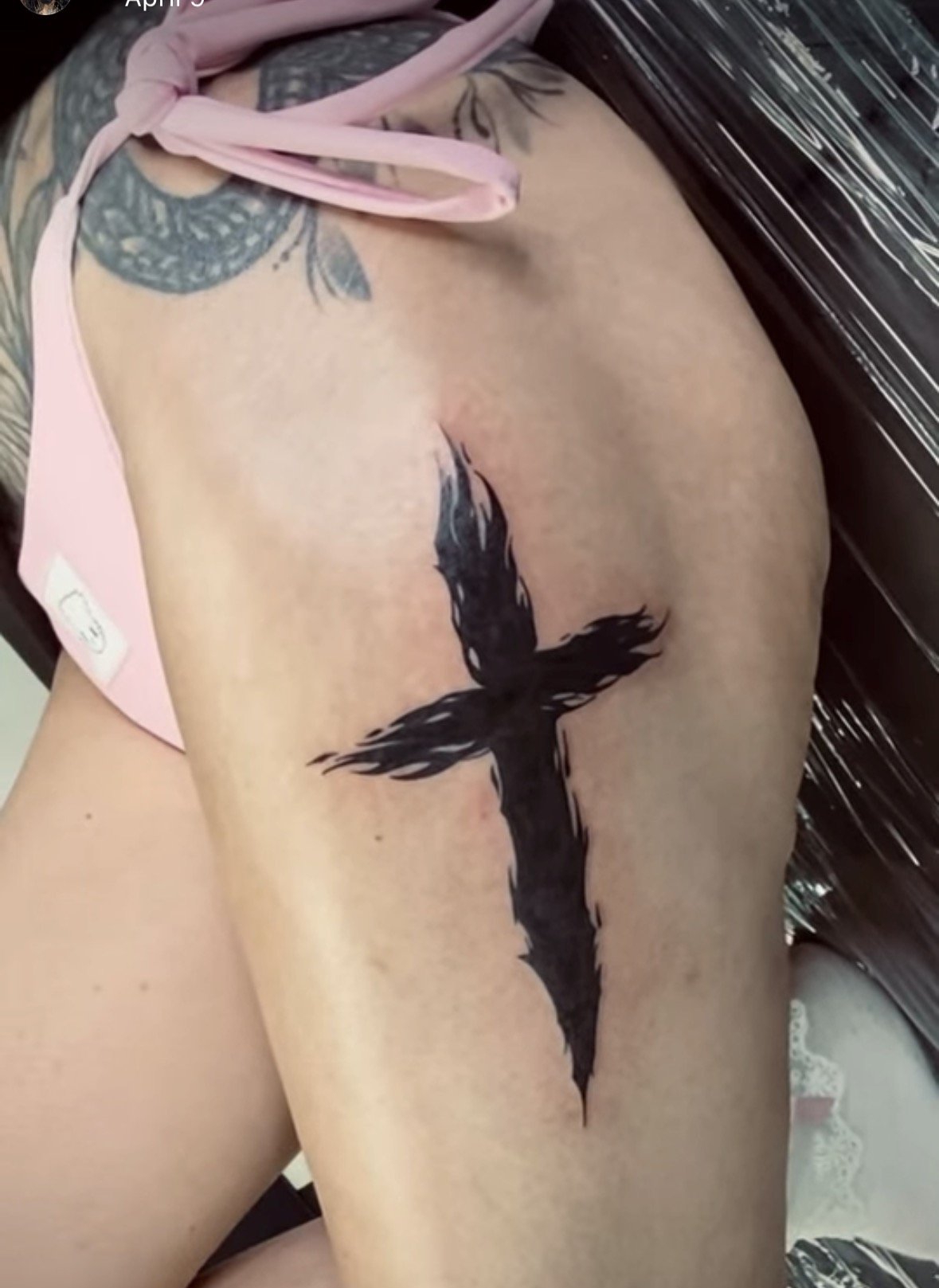 Blackwork tattoo of a black cross on a person's thigh by tattoo artist Agua at Floating Streams Tattoo in the Arts District of Downtown Los Angeles.