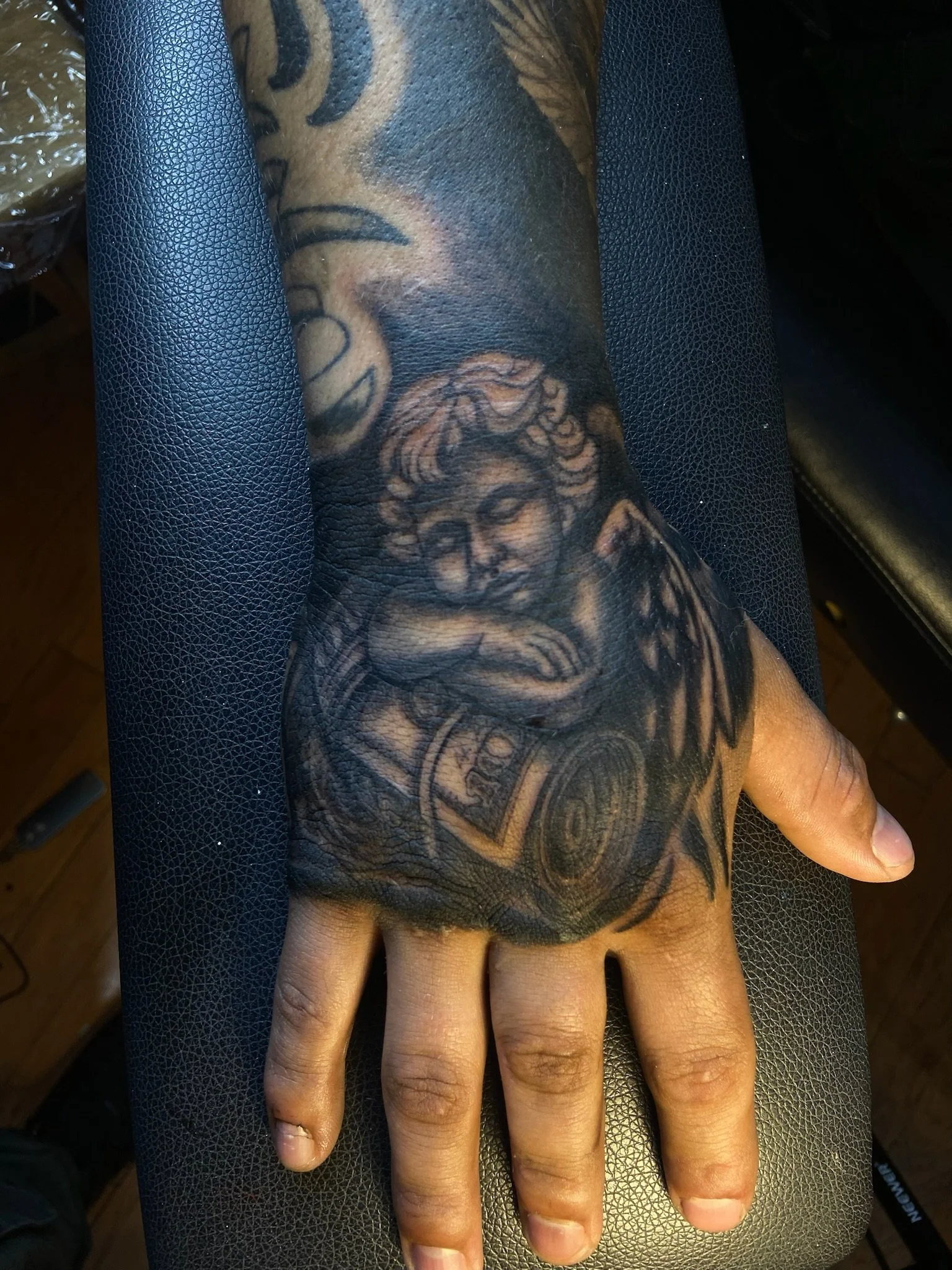 Close-up of a person's arm with a detailed black and grey tattoo of a woman's face, adorned with roses and decorative elements.