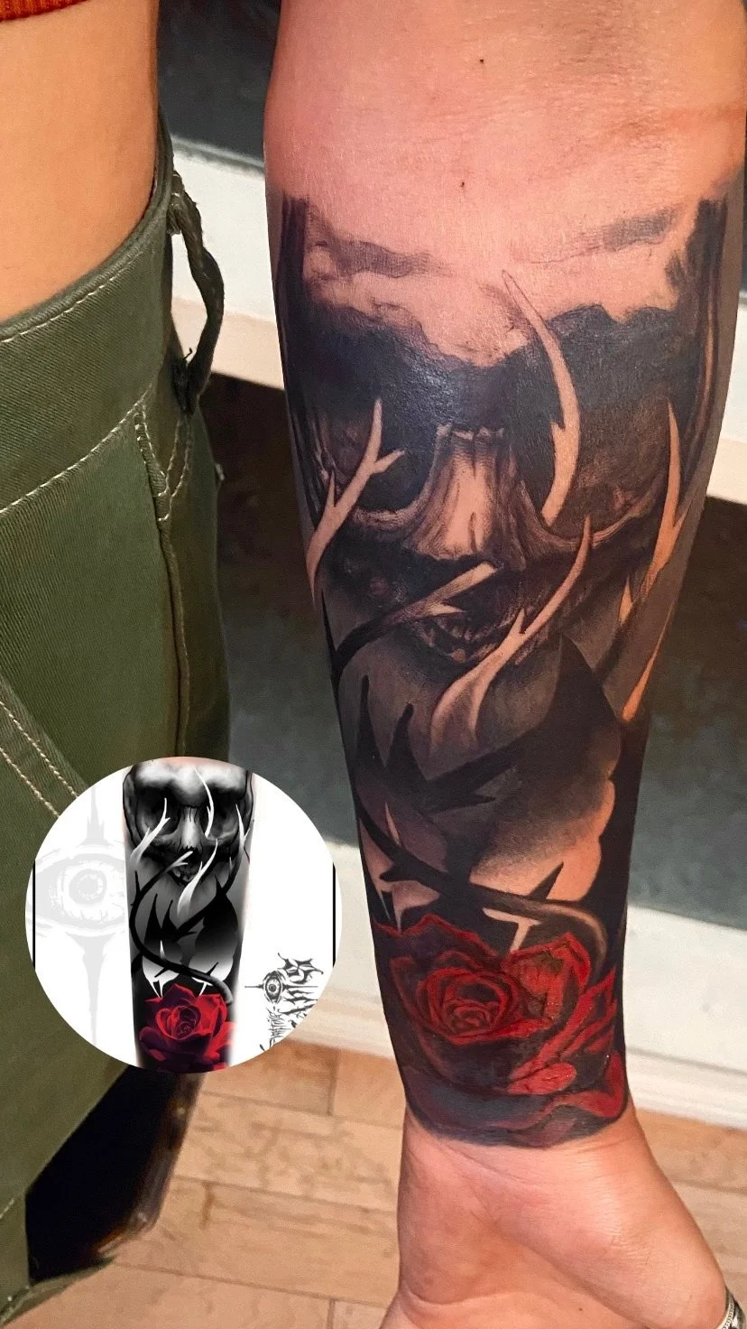 Close-up of a person's arm with a large, detailed black and gray and red tattoo depicting a mountain, stormy clouds, and roses.
