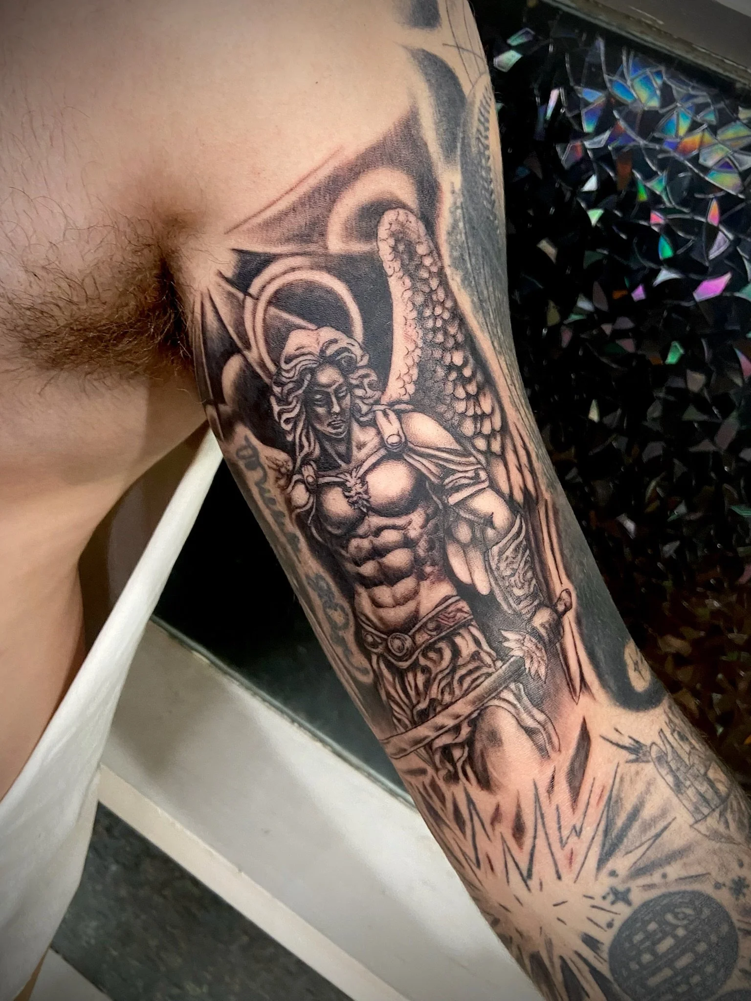 Tattoo of a woman with wings on a person's arm, with additional designs and patterns surrounding it.