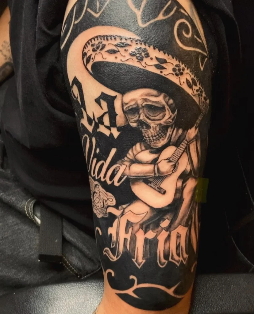 Tattoo of a skeleton wearing a large sombrero playing a guitar.