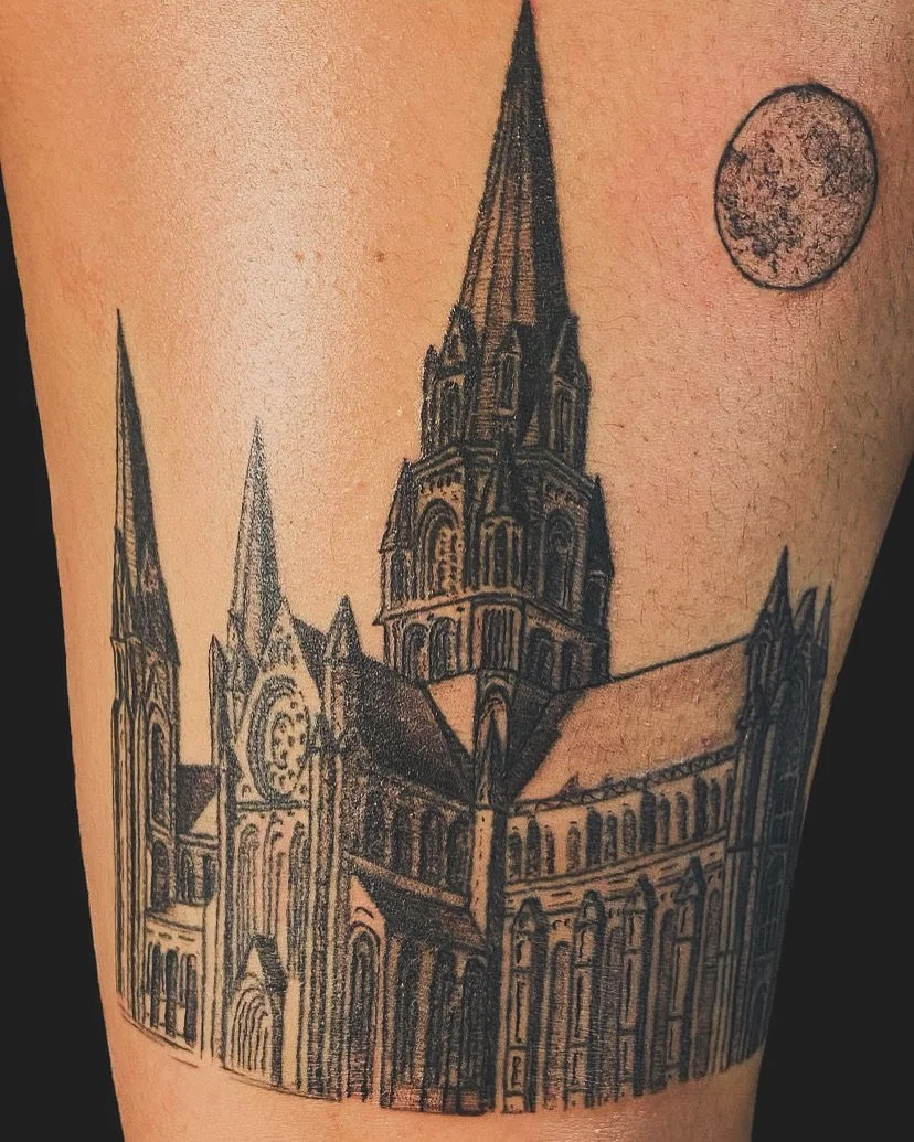 Black line tattoo of a Gothic-style church with tall spires, a large rose window, and detailed architecture, with a full moon in the sky.