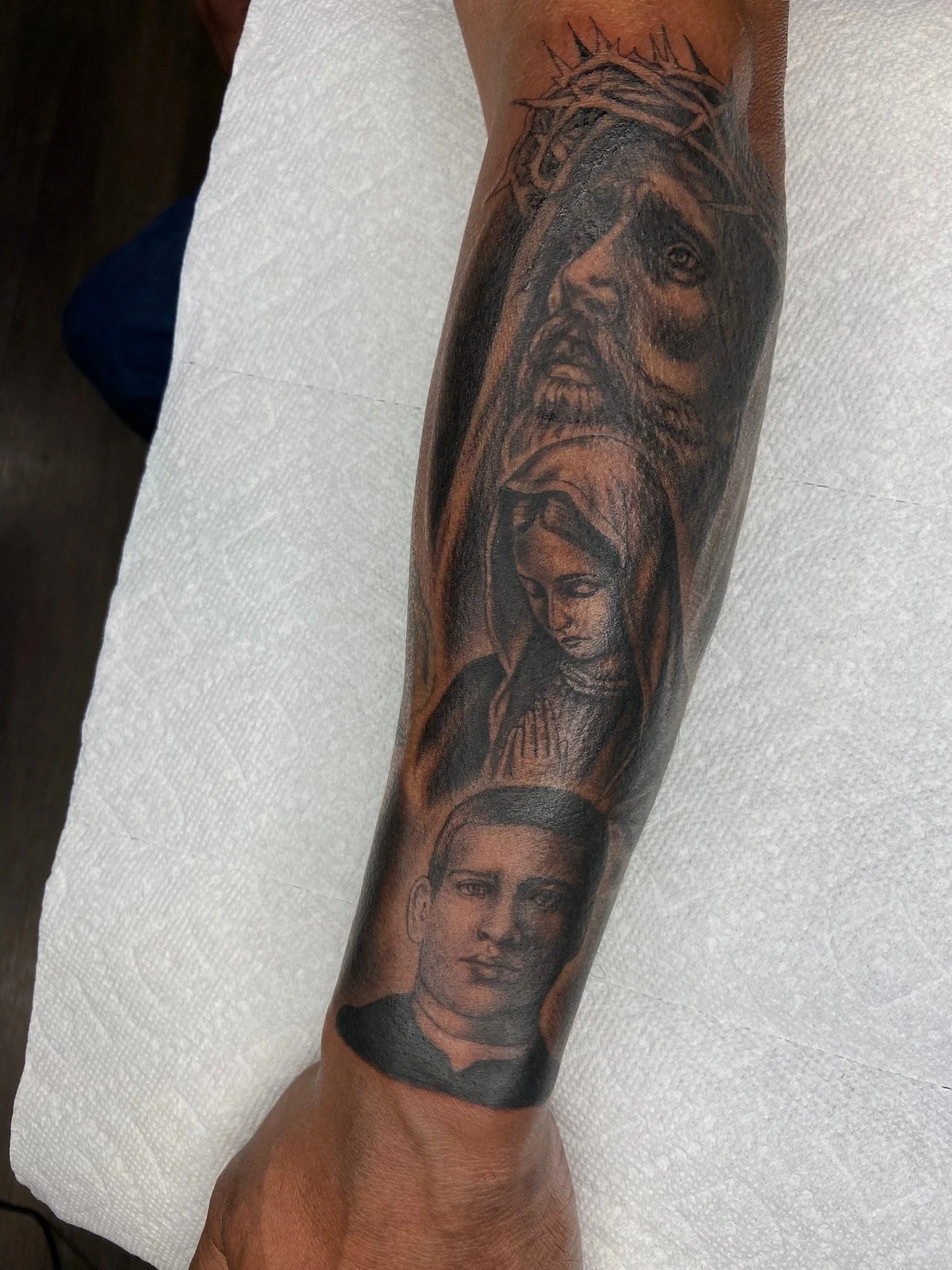 Tattoo of a person with long hair and a beard wearing a crown of thorns.